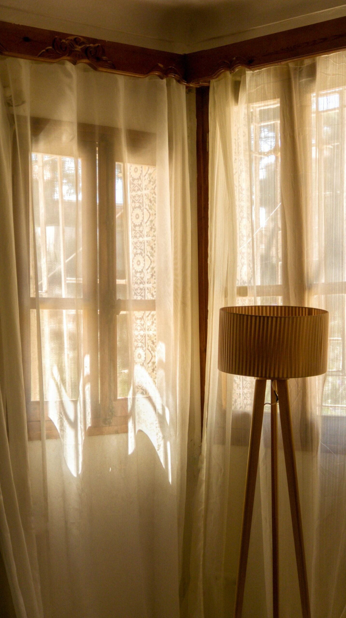 Vintage lamp and sheer curtains in a warmly lit room.