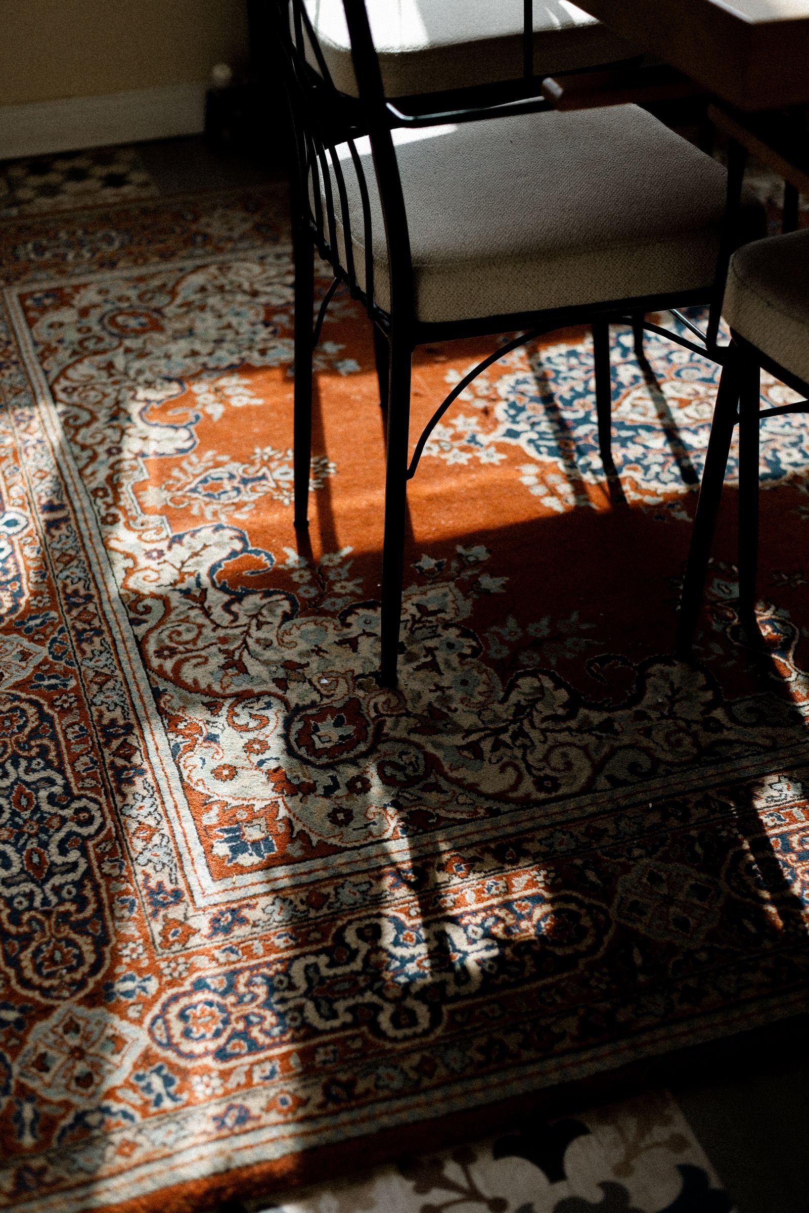 Sunlit room with an ornate Persian rug and chairs.