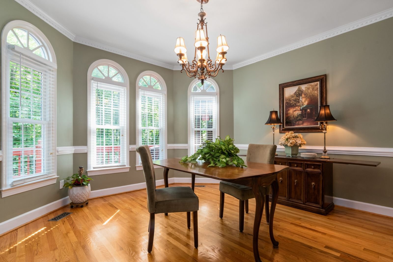 Dining room with arched windows, hardwood floor and a chandelier.