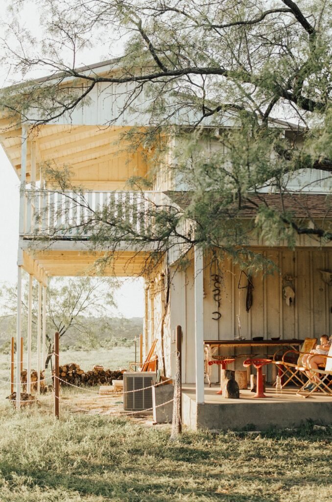 Rustic ranch house with a wooden porch among trees.