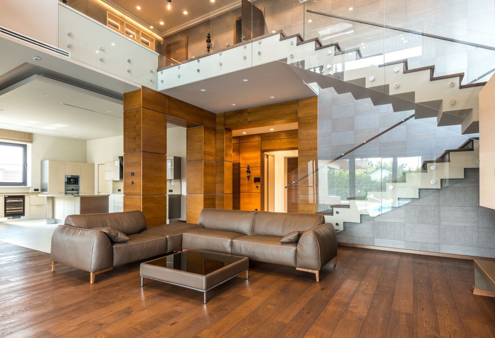 Living room with leather sofas, parquet flooring and a glass staircase.