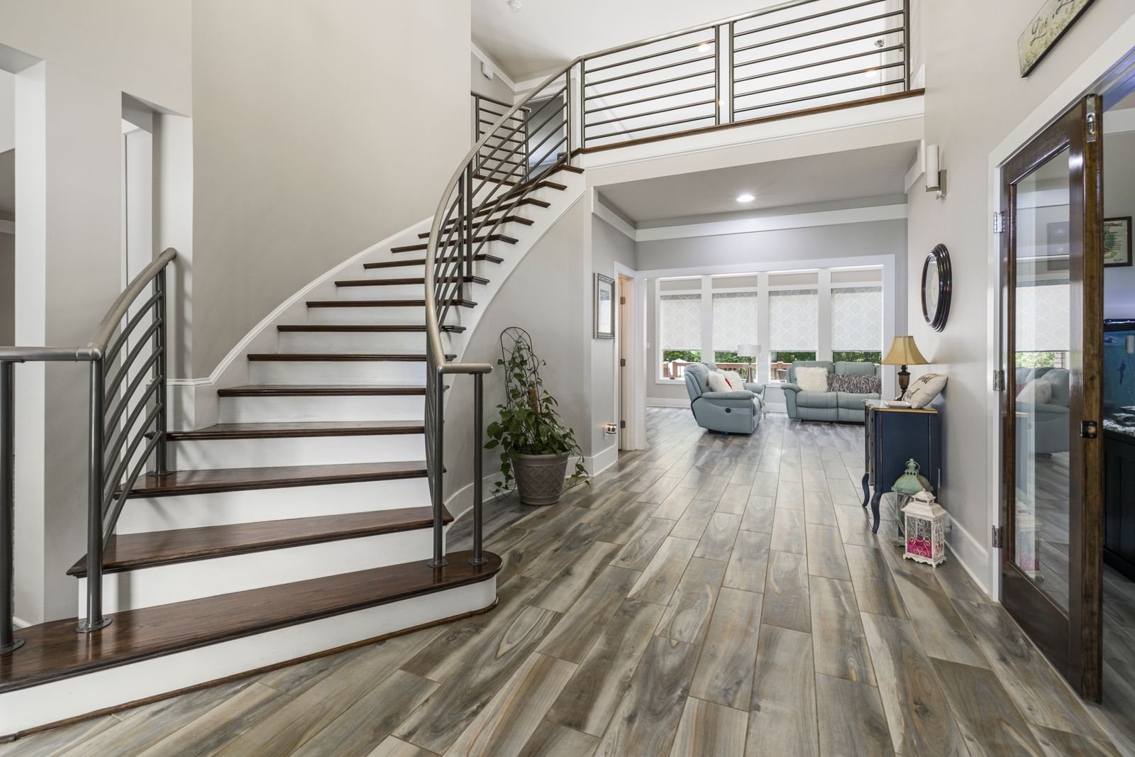 Modern home interior with a curved staircase and steel handrail.