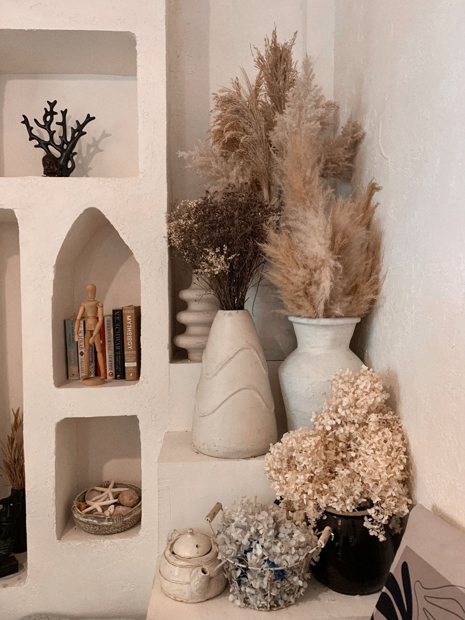 Shelves with dried flowers and vases in a rustic room.