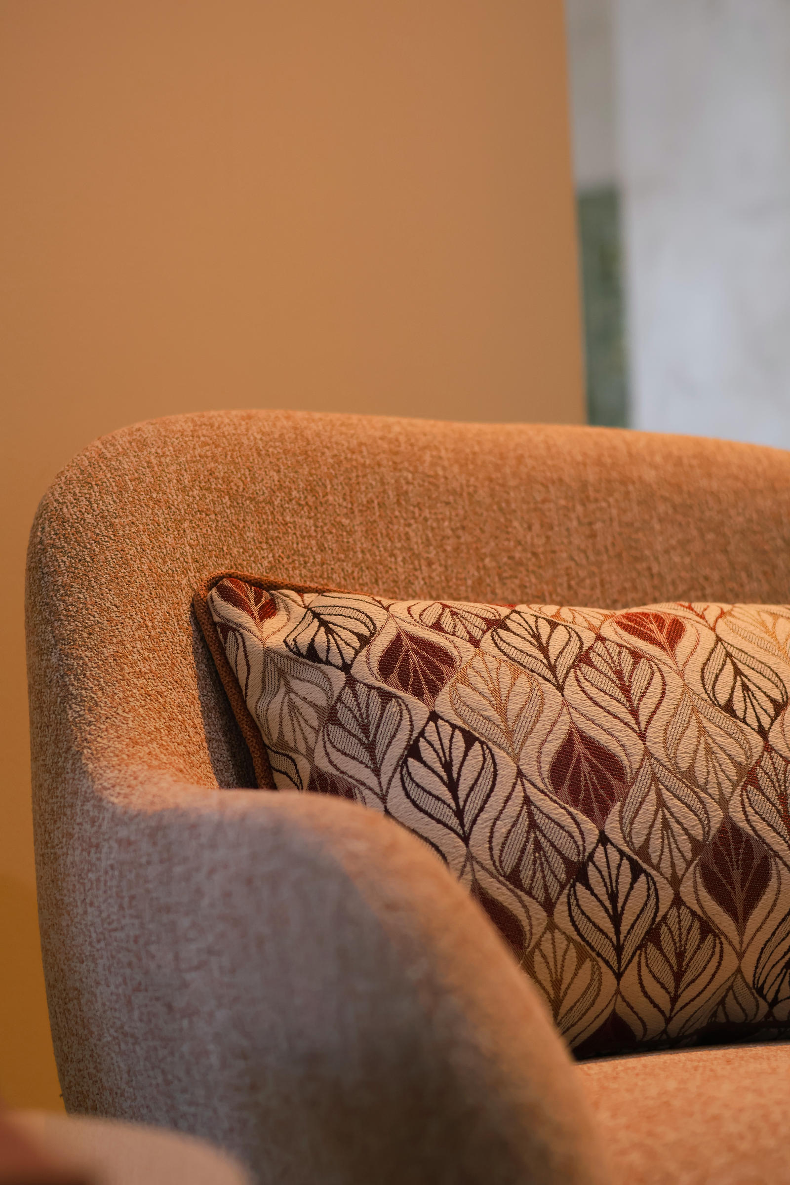 Armchair with a patterned pillow in warm indoor light.