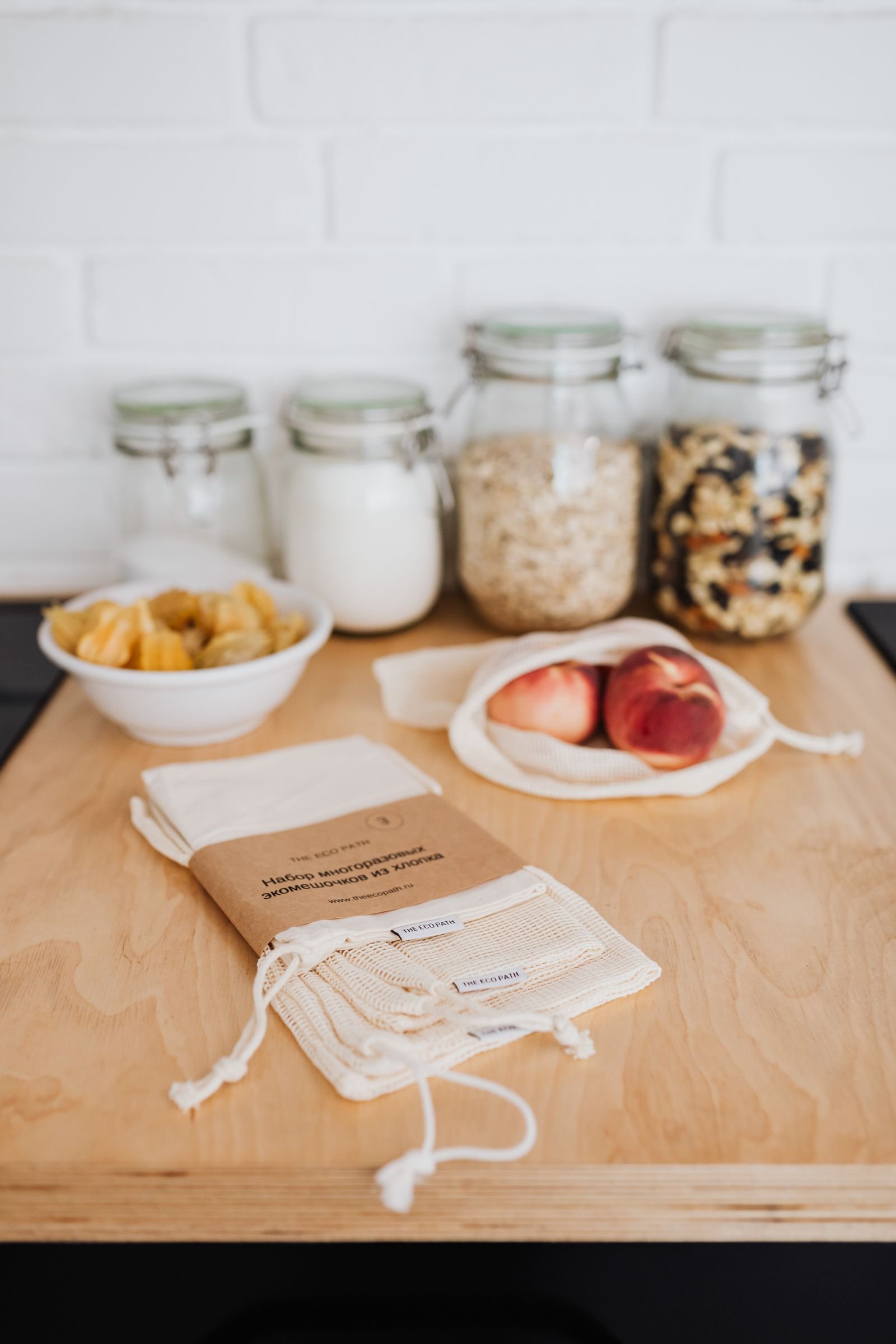 Reusable cloth bags, glass jars and organic food on a wooden surface.