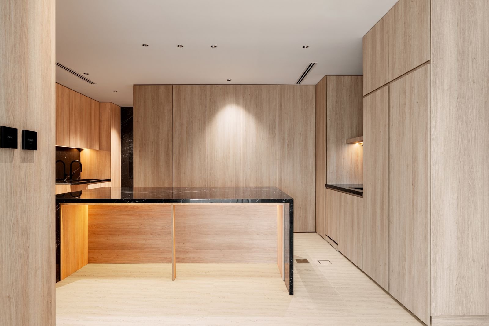 Modern kitchen with wood paneling and dark marble countertops.