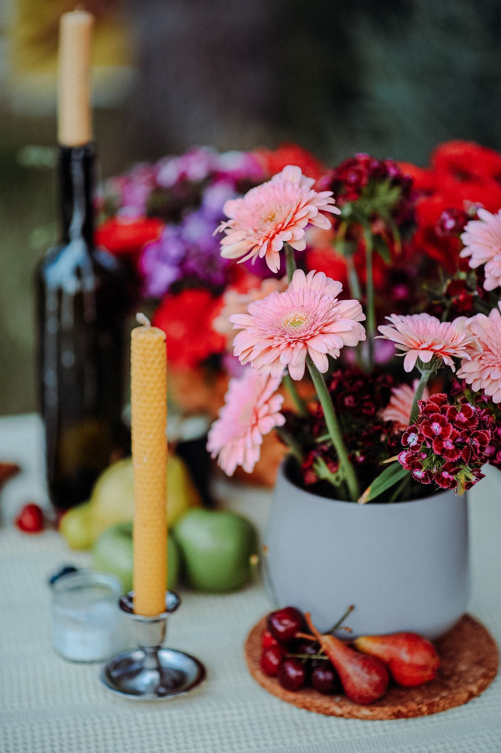 Pink gerbera flowers arranged beside a wax candle.