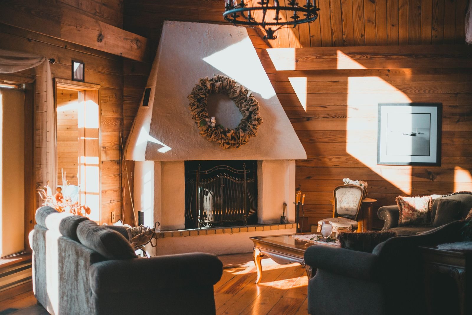 Sunlit living room with wooden walls and a fireplace.