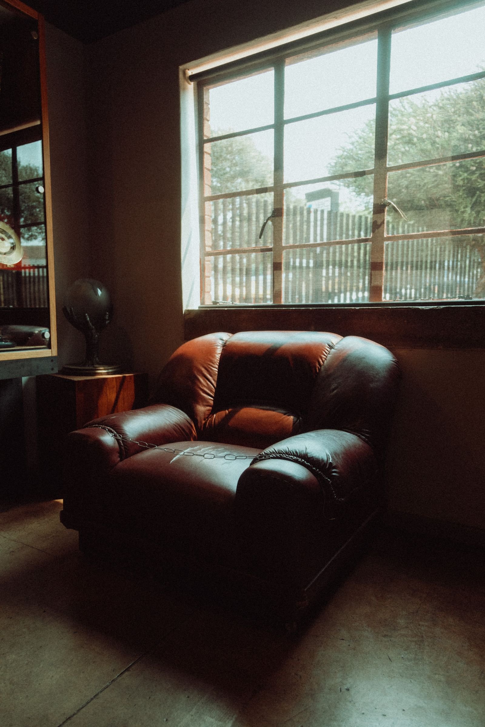 Leather armchair by a sunlit window in a warm room.