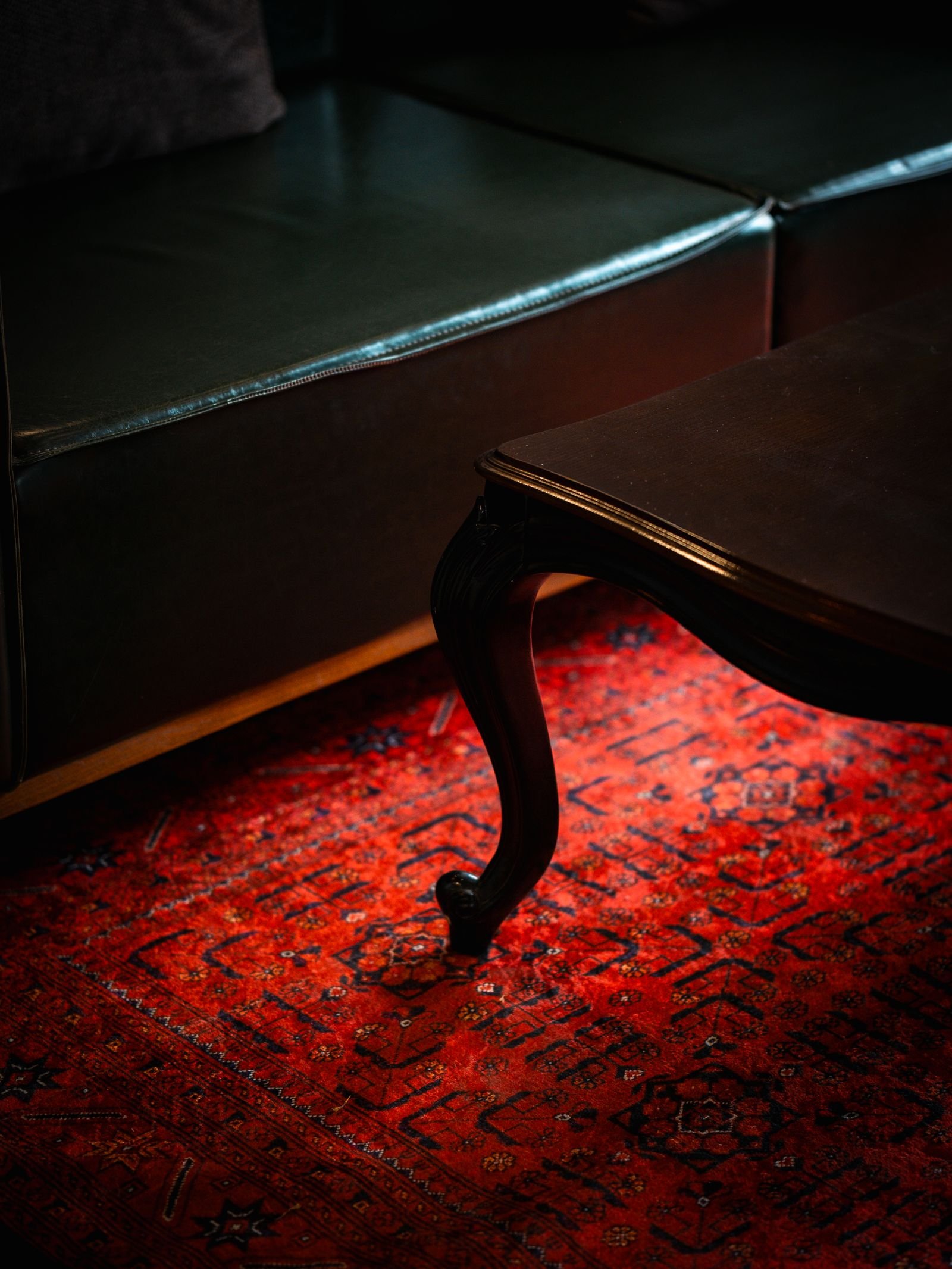 Persian-style rug lying flat under a wooden table in a living room corner.