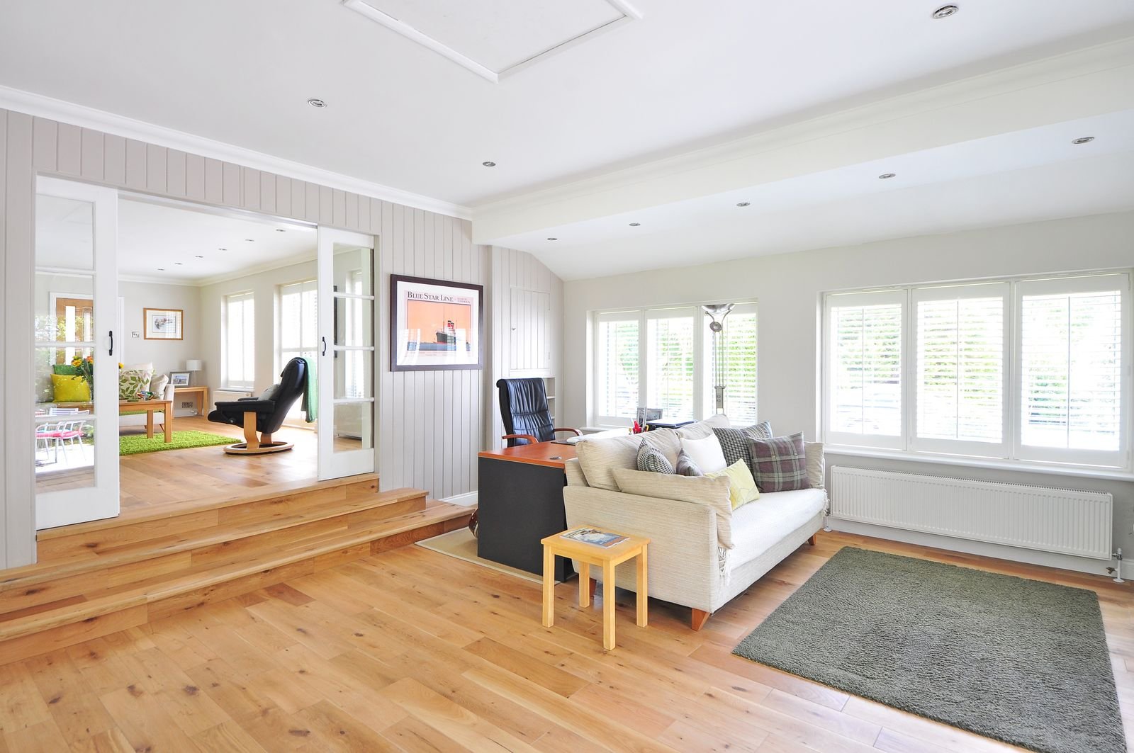 Bright modern living room with wooden floors and a white couch on a dark rug.