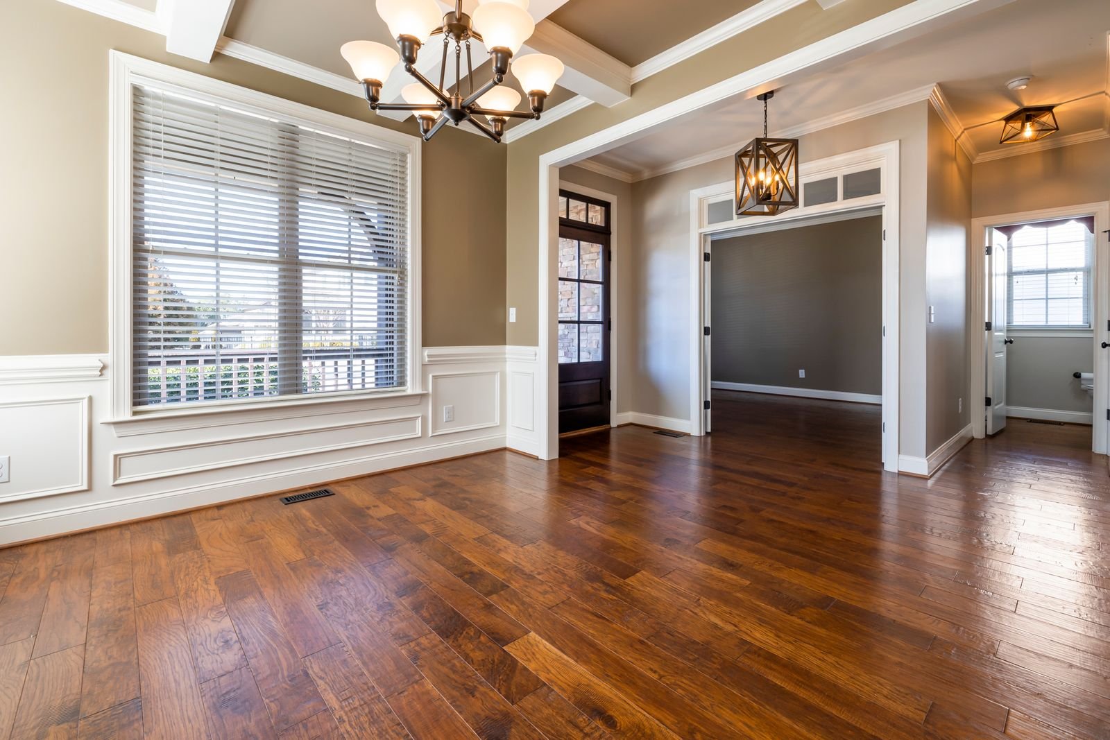 Elegant room with parquet wood flooring, a chandelier and natural light.
