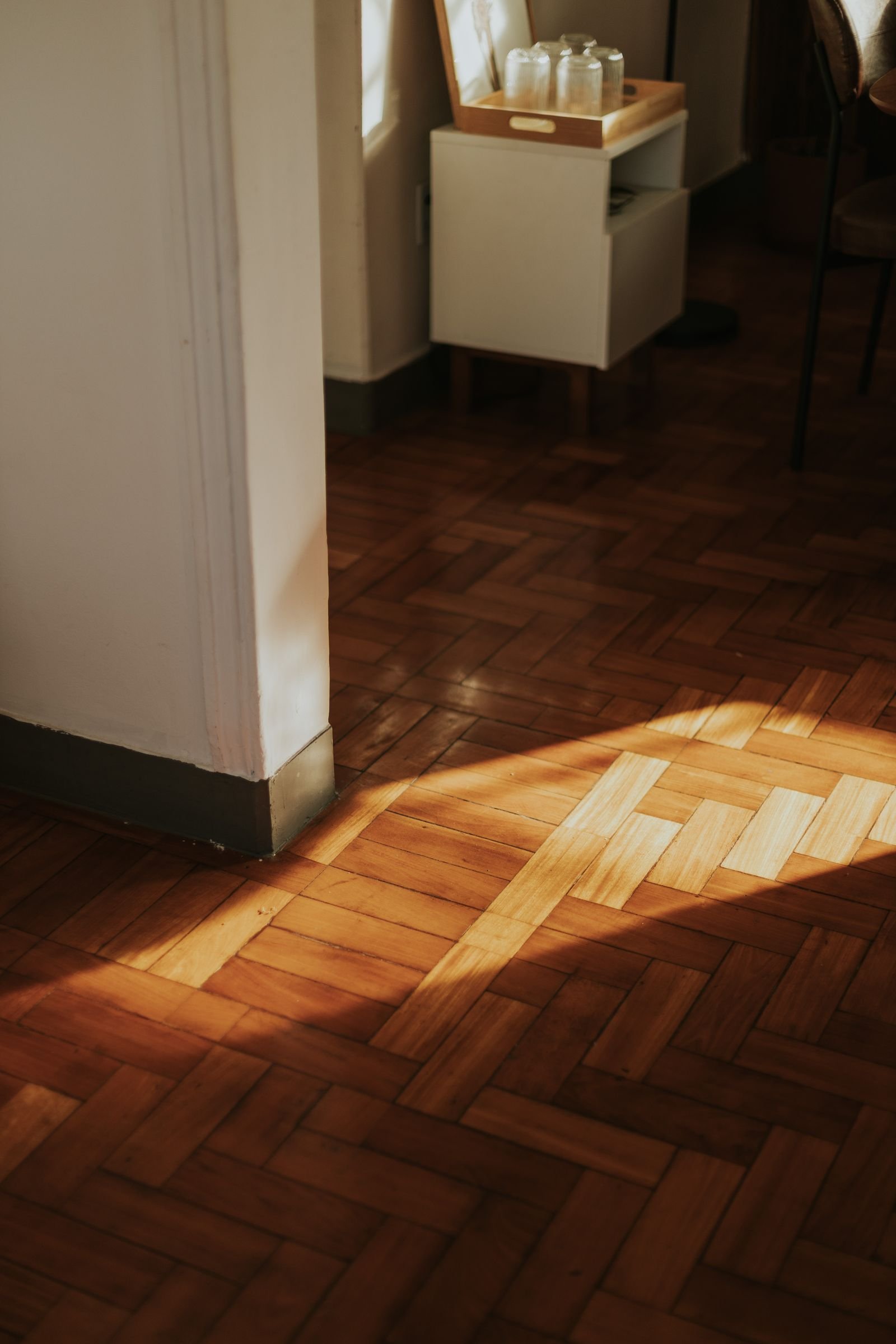 Warm sunlight falling on a wooden parquet floor in a cozy room.