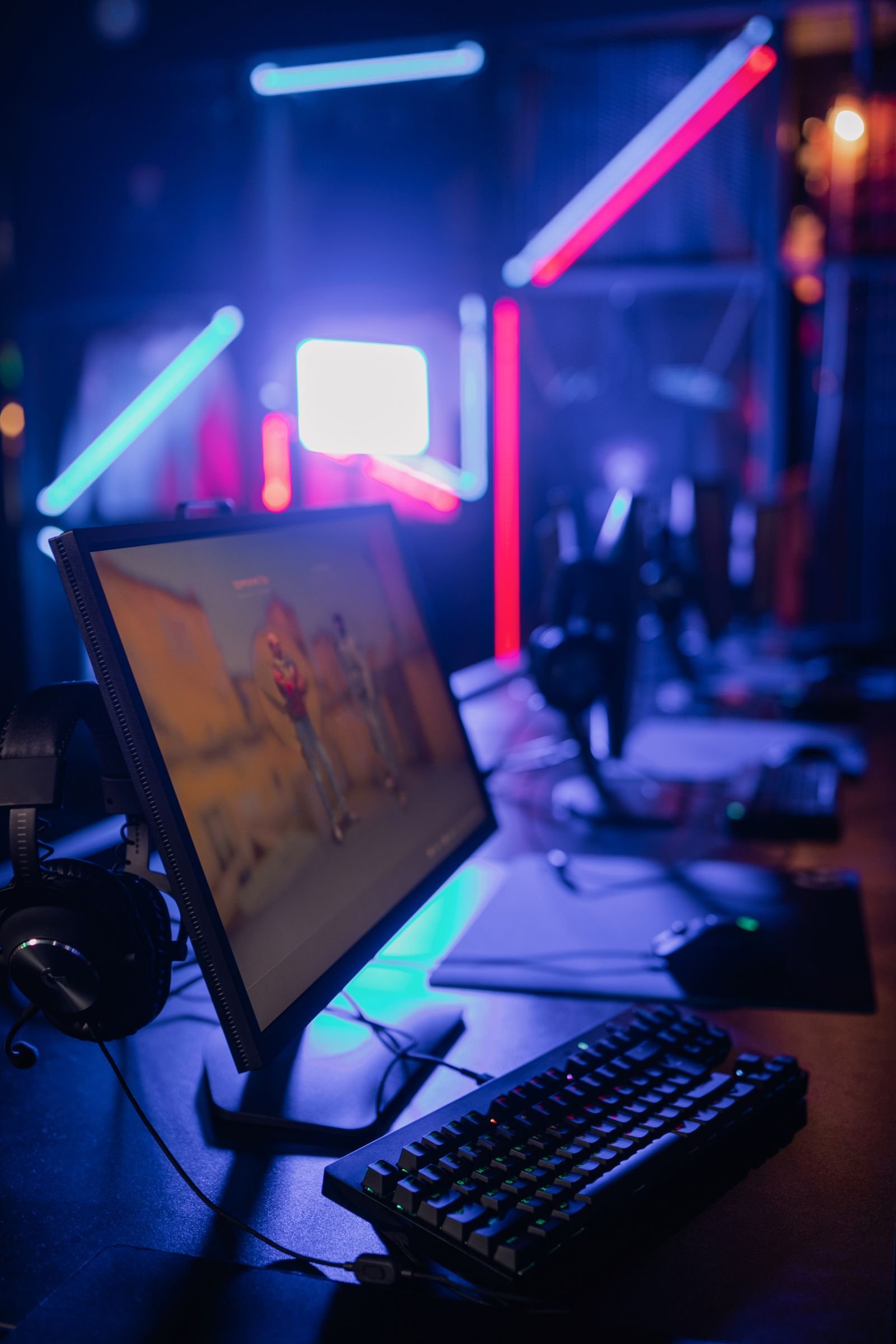Modern gaming setup with a monitor, keyboard and neon lighting.