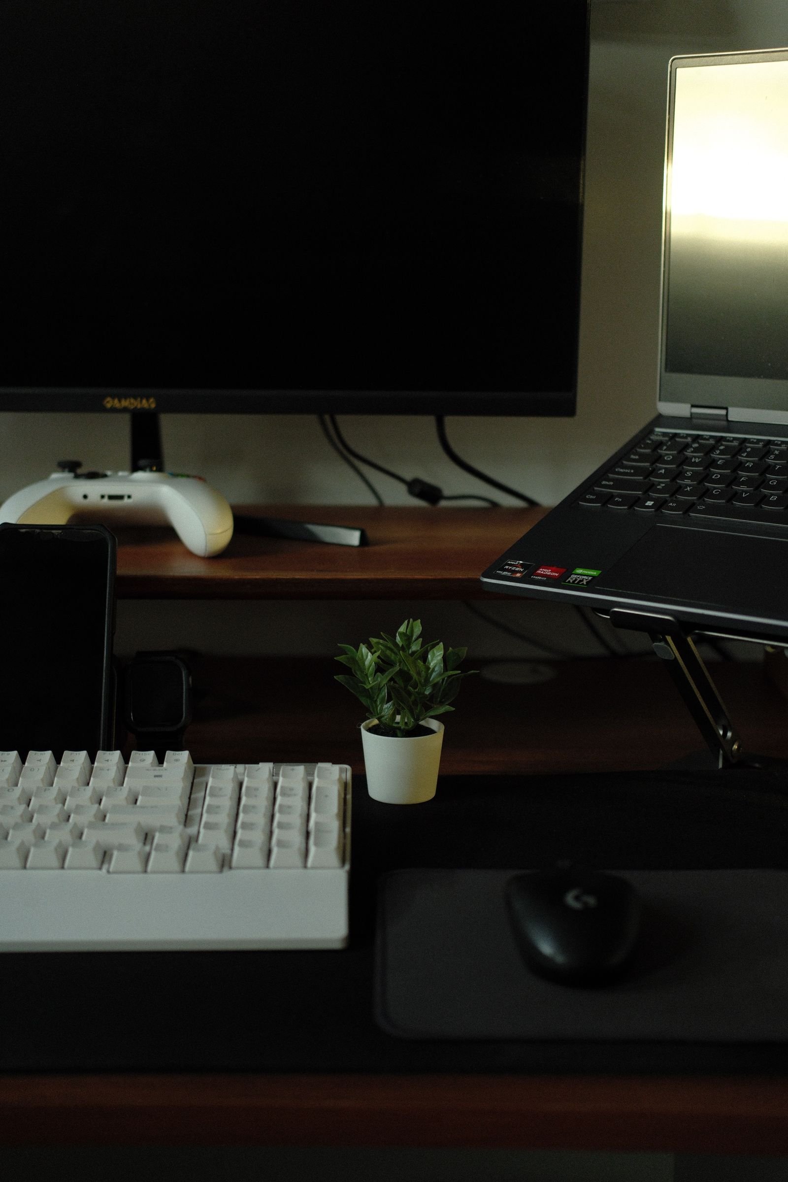 Minimalist desk with a keyboard, a laptop and a game controller.