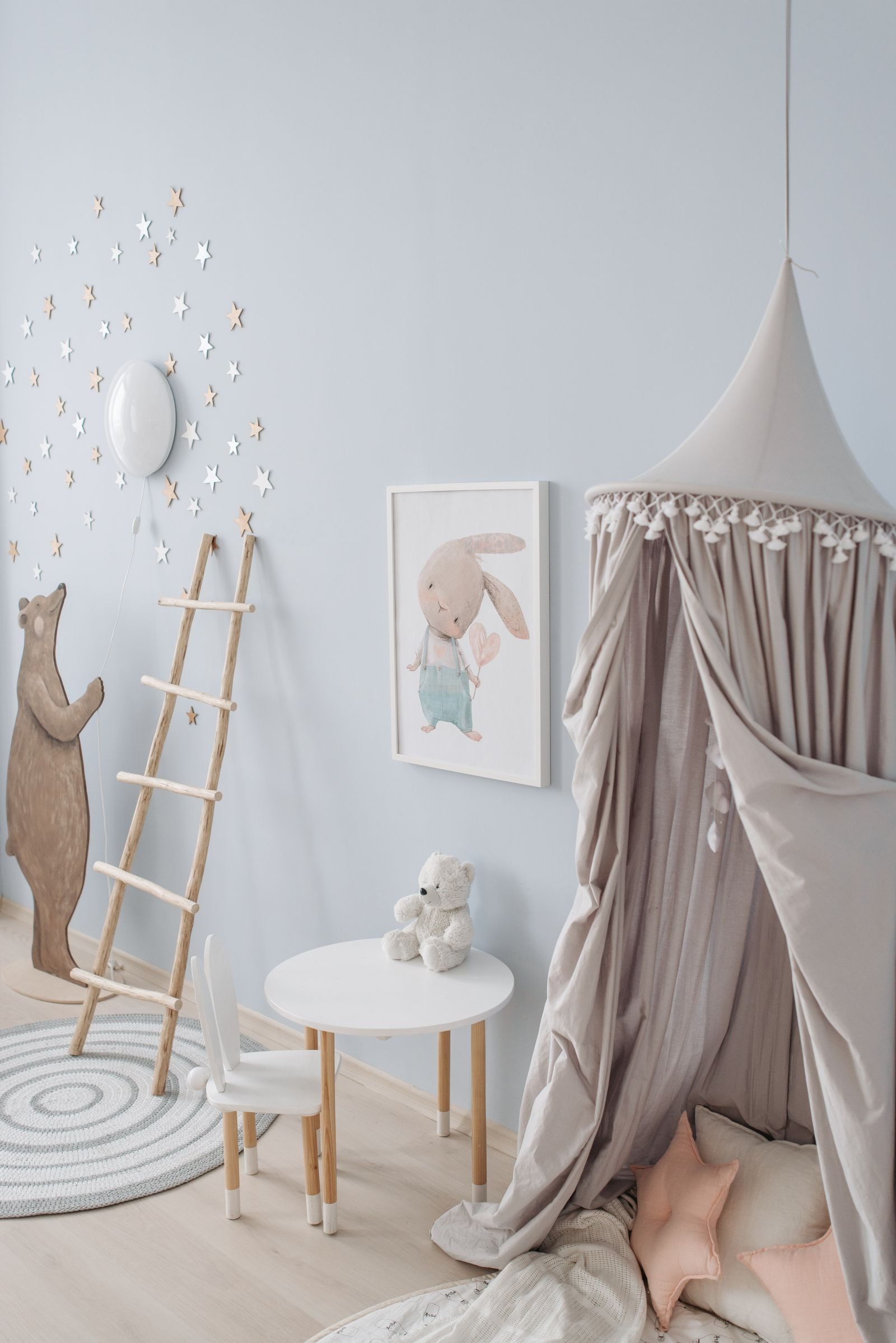 Children's room with a canopy tent, wooden toys and pastel wall decor.