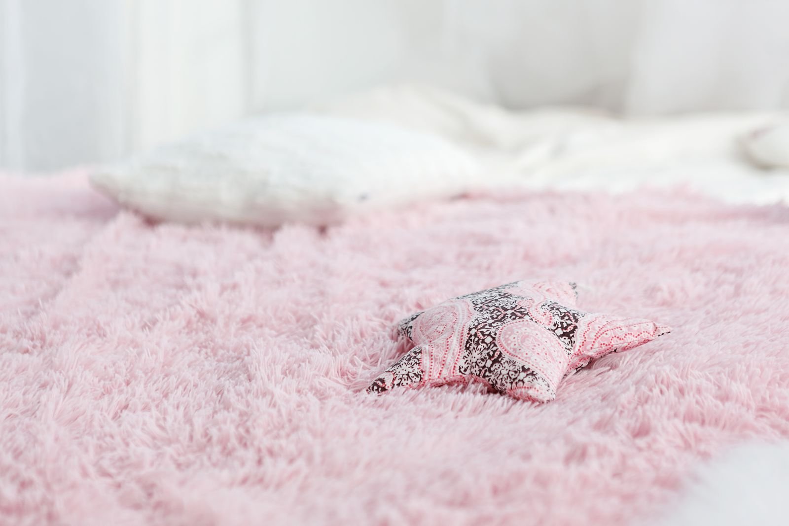 Star-shaped pillow on a soft pink fuzzy blanket.