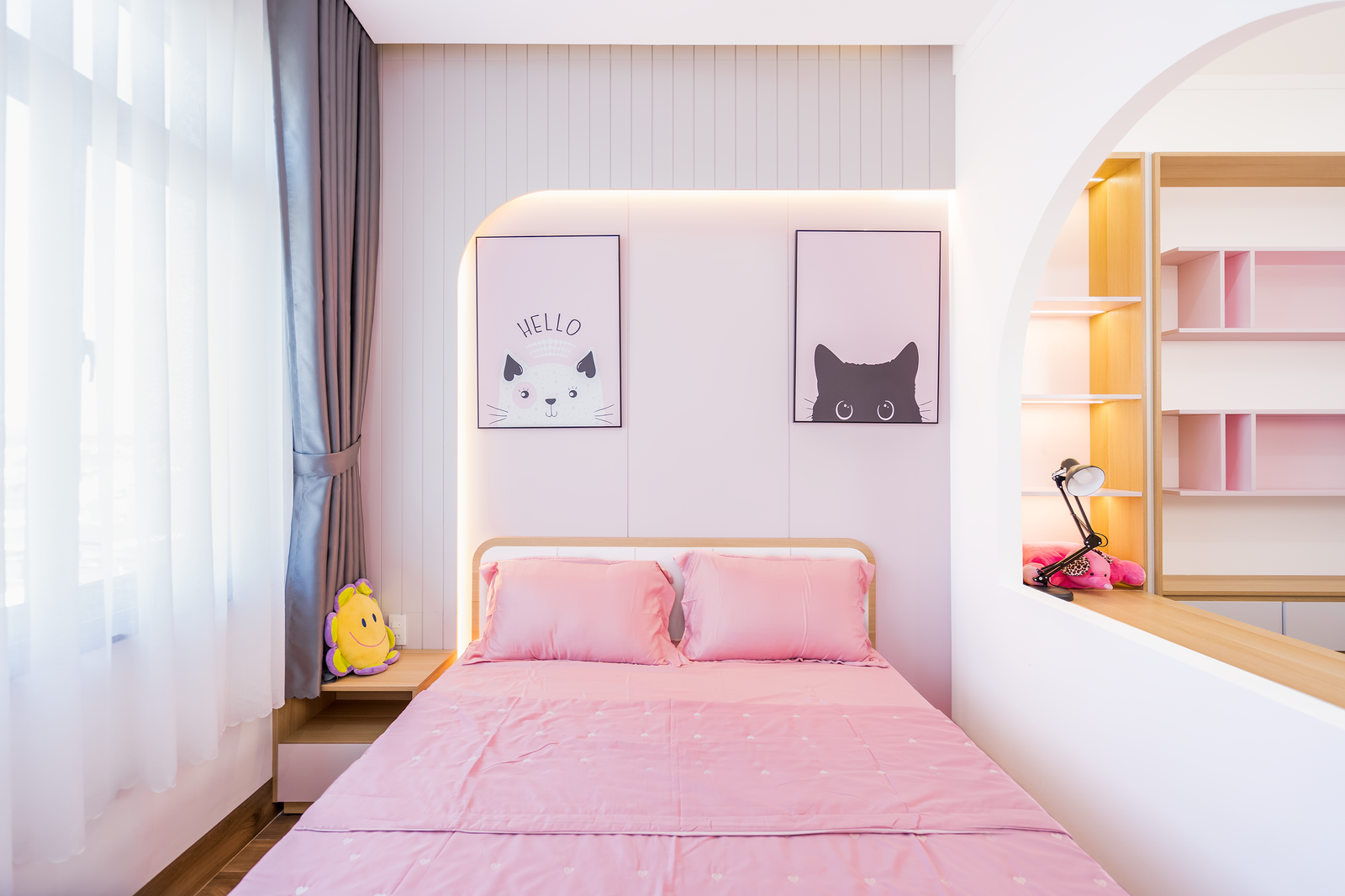 Bright bedroom with pink bedding and framed cat artwork.