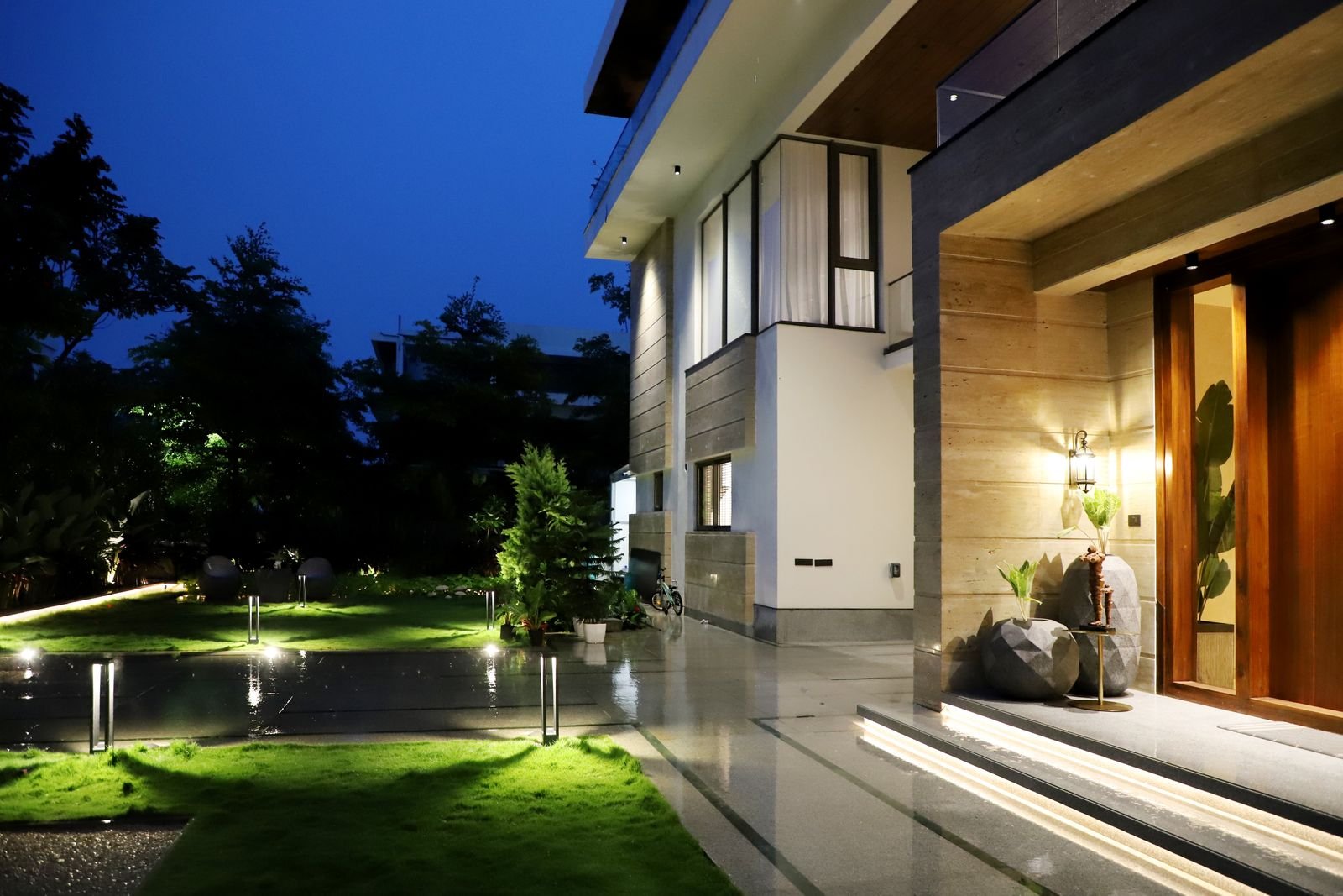 Modern house and garden lit up at night.