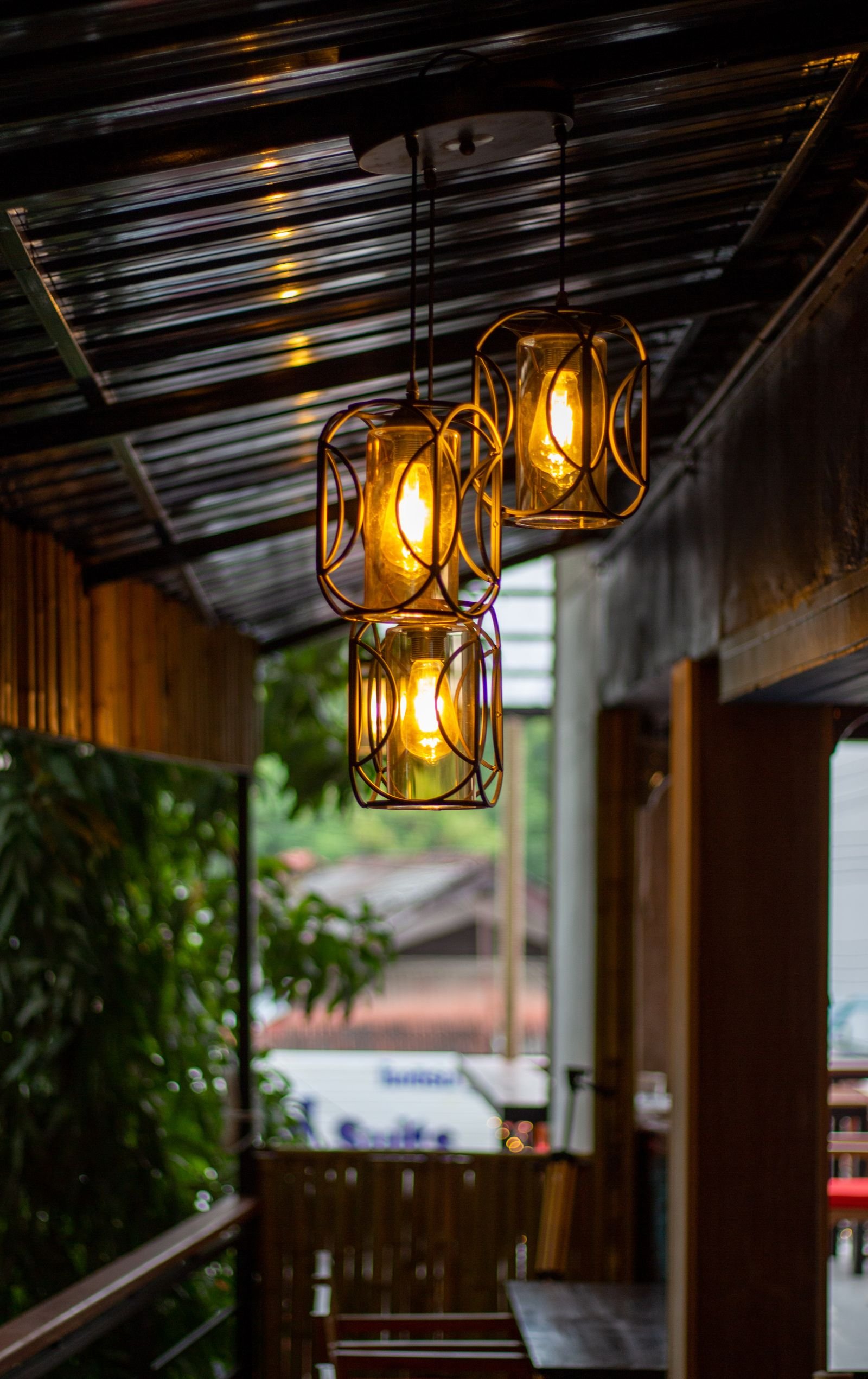 Three glass lanterns hanging from the ceiling of a covered porch.