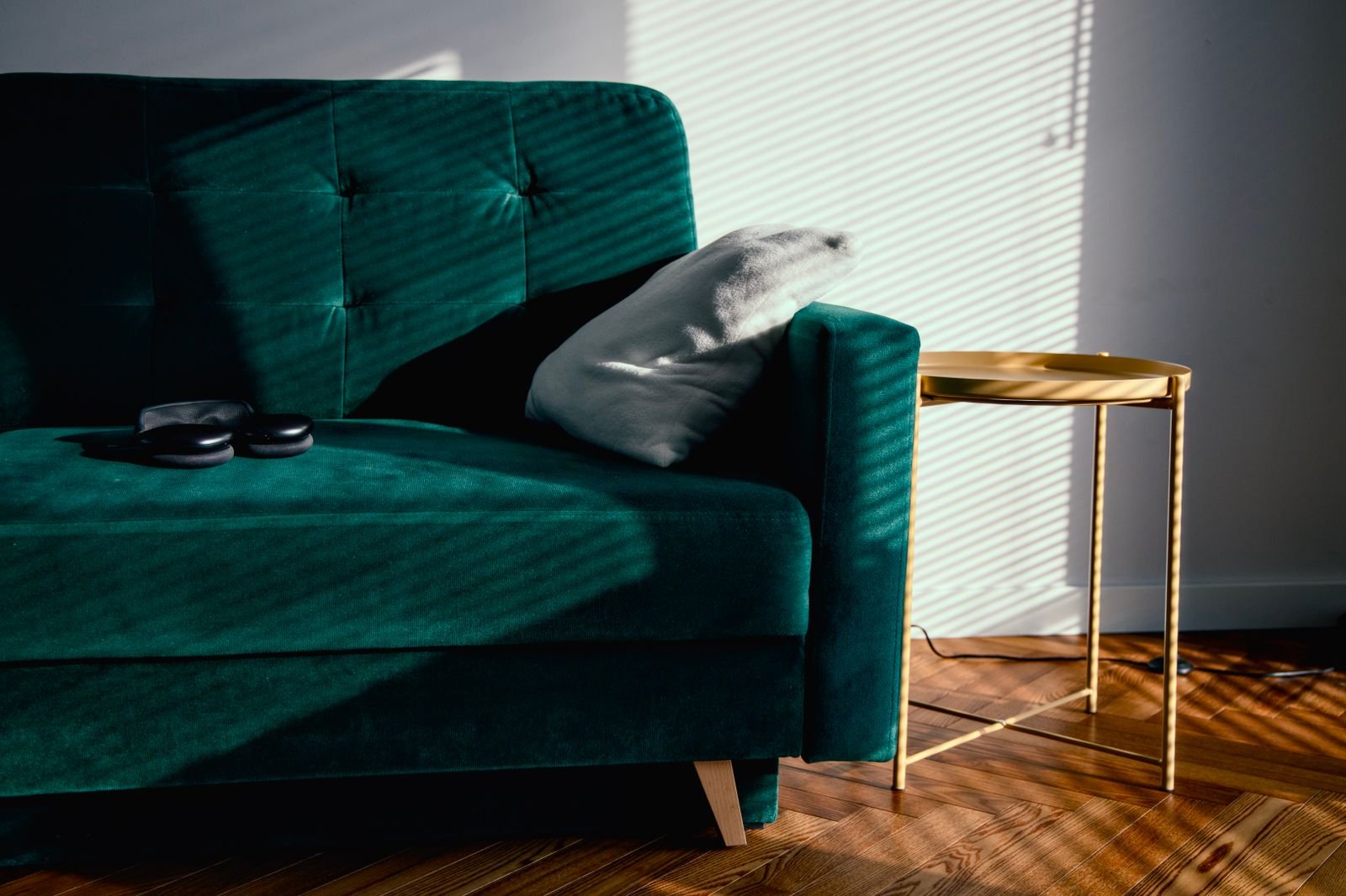 Sunlit living room with a green velvet sofa and minimal decor.