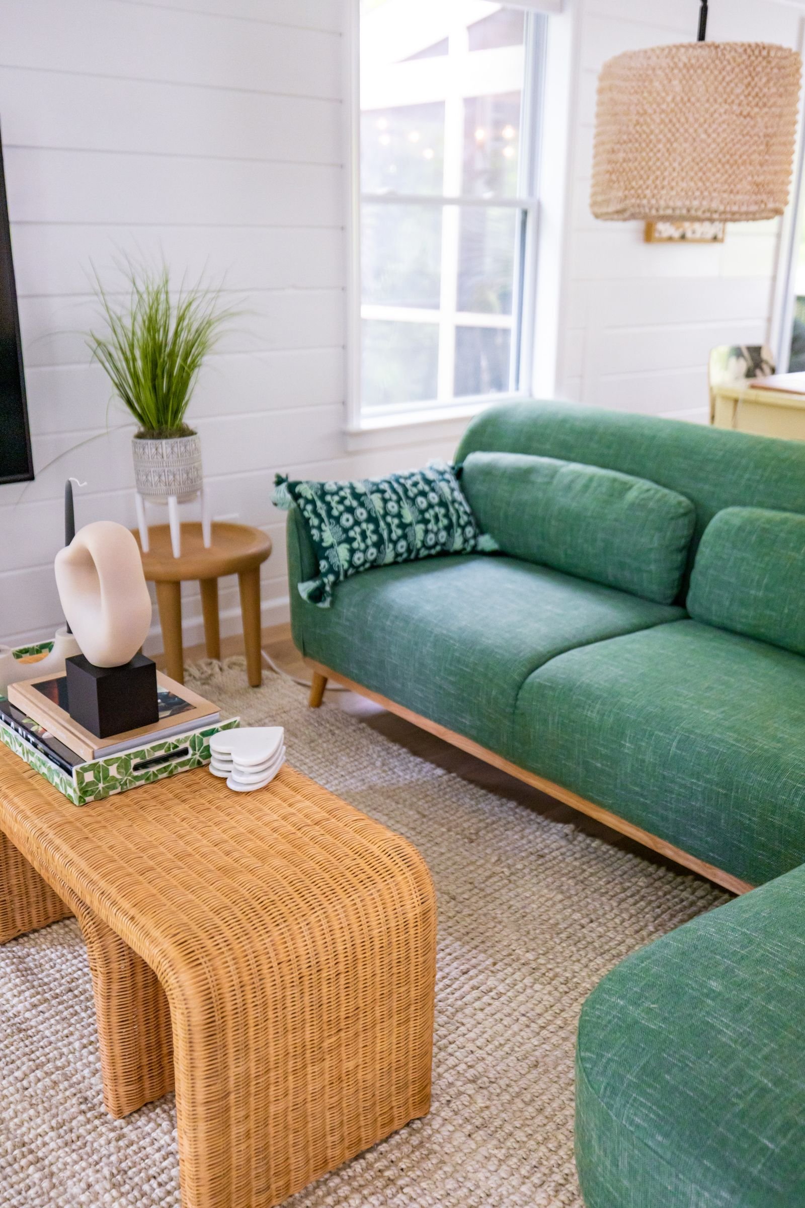 Relaxed living room with a green sofa and a rattan table.