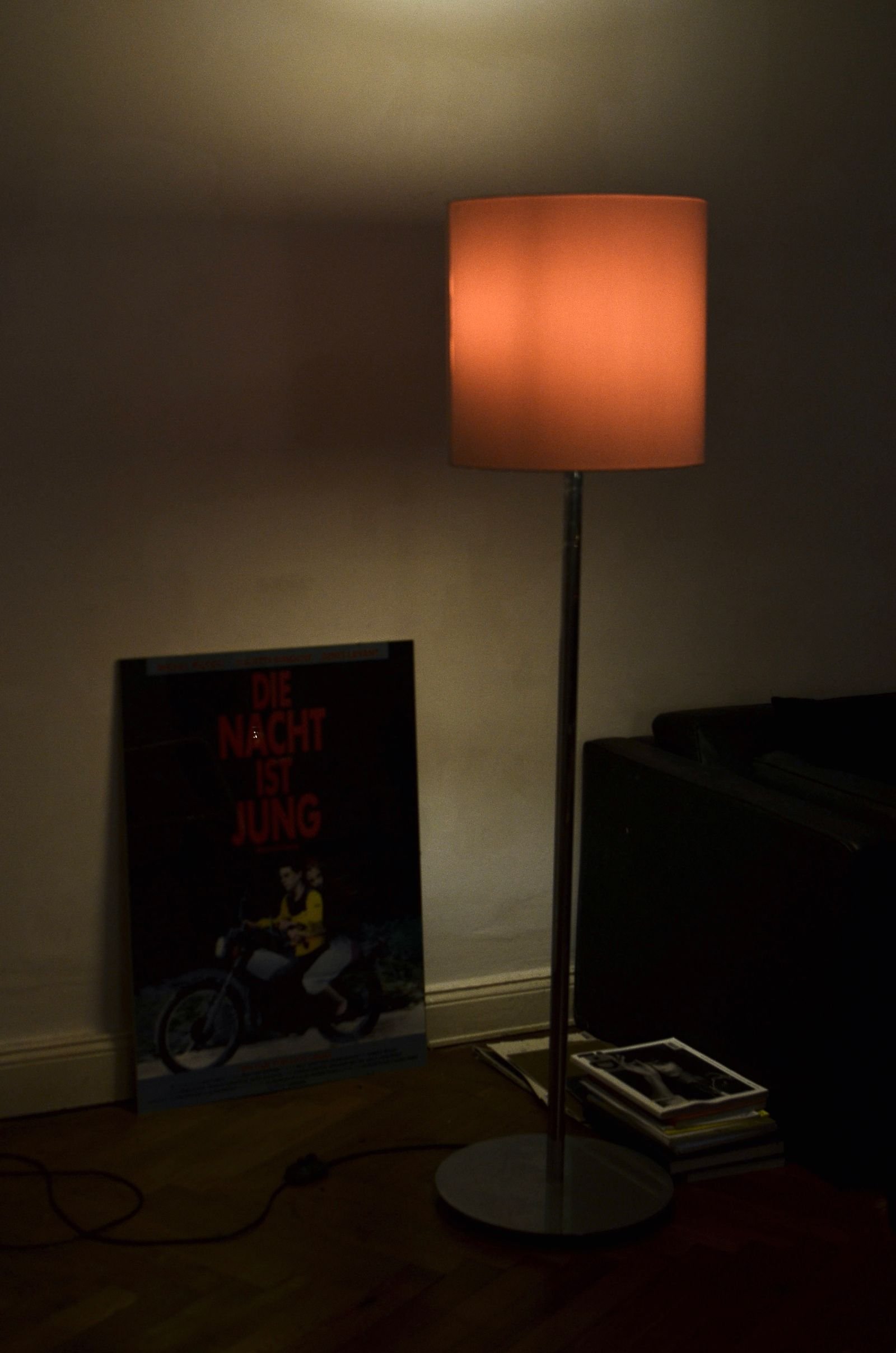 Floor lamp glowing beside a sofa in a cozy apartment living room.