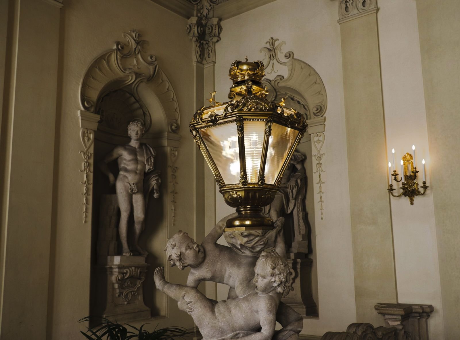Classic interior with ornate sculptures and a large lamp.