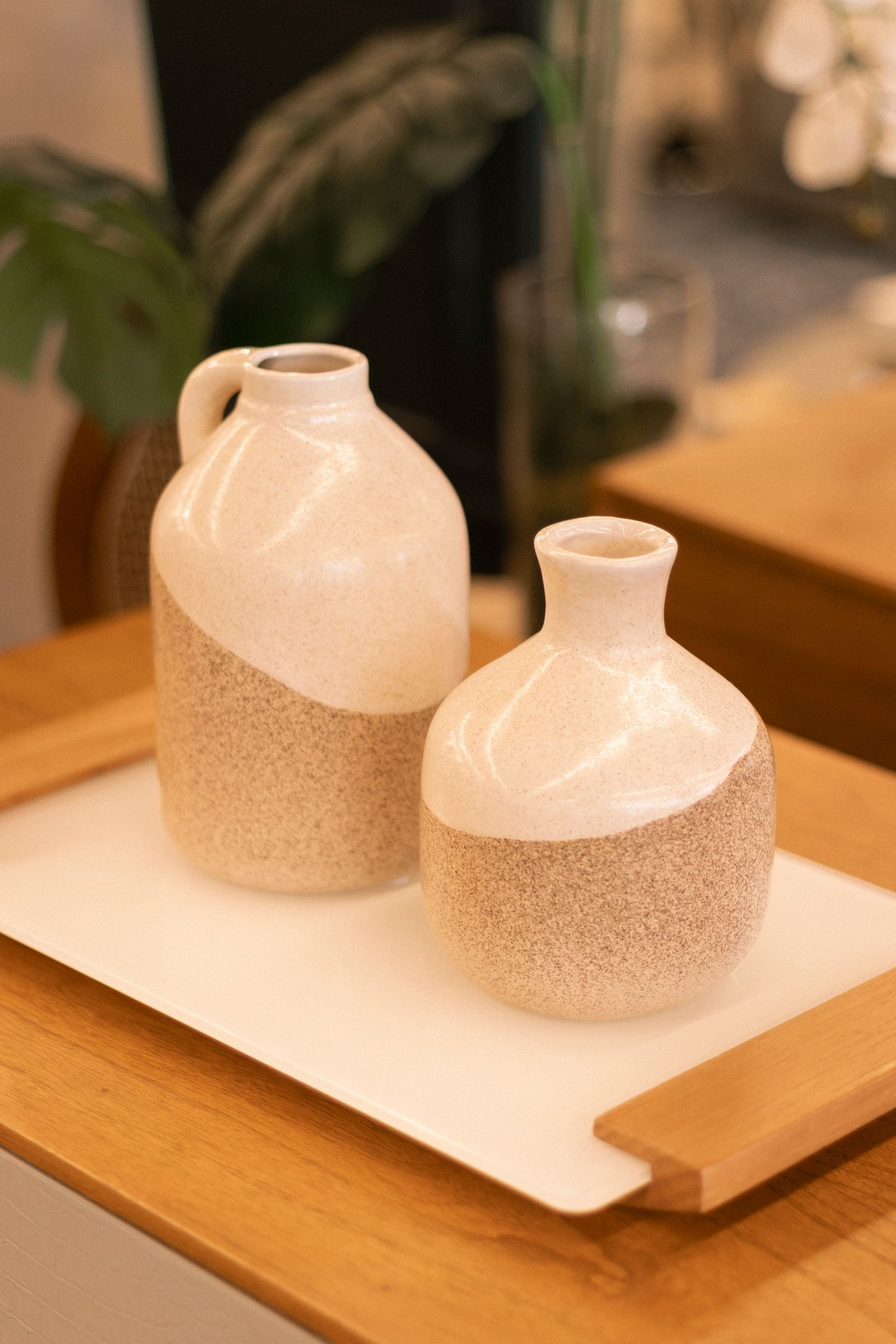 Two ceramic vases on a wooden tray in a minimalist style.
