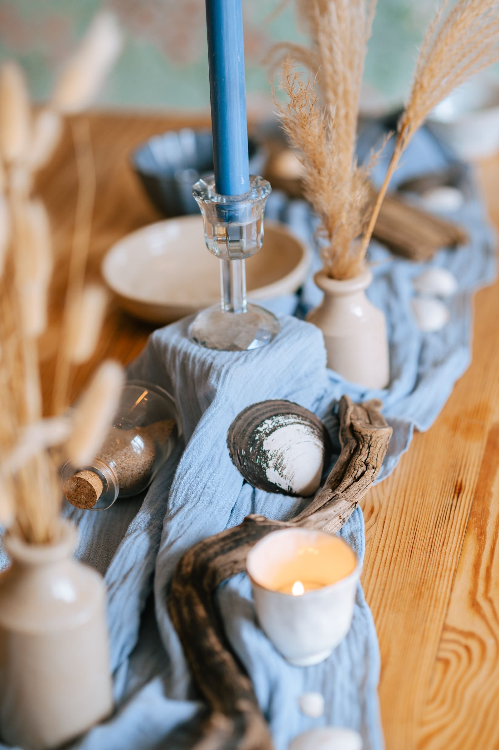 Coastal table setting with candles, driftwood and natural decor.