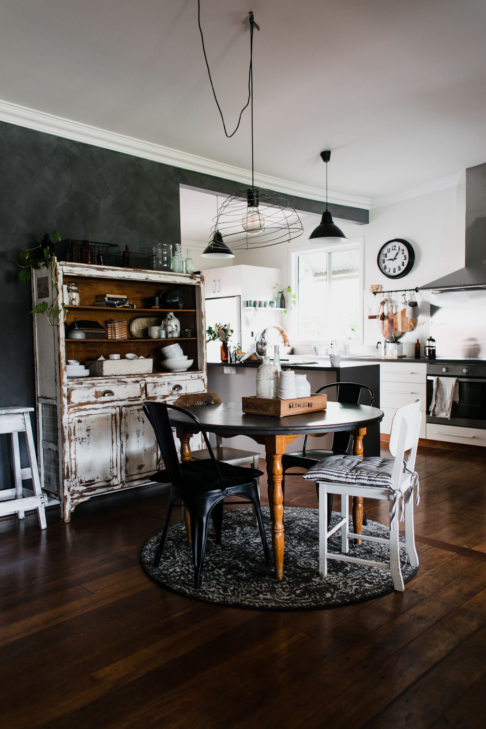 Cozy kitchen with a round wooden table, chairs and a wooden cupboard.
