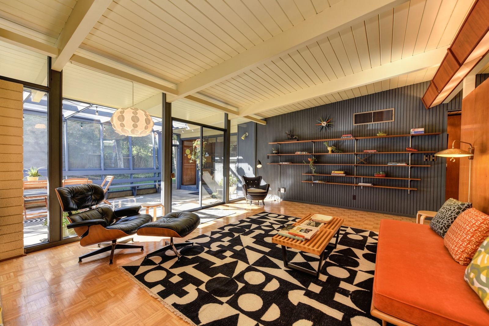 Mid-century modern living room with armchairs and shelves in natural light.