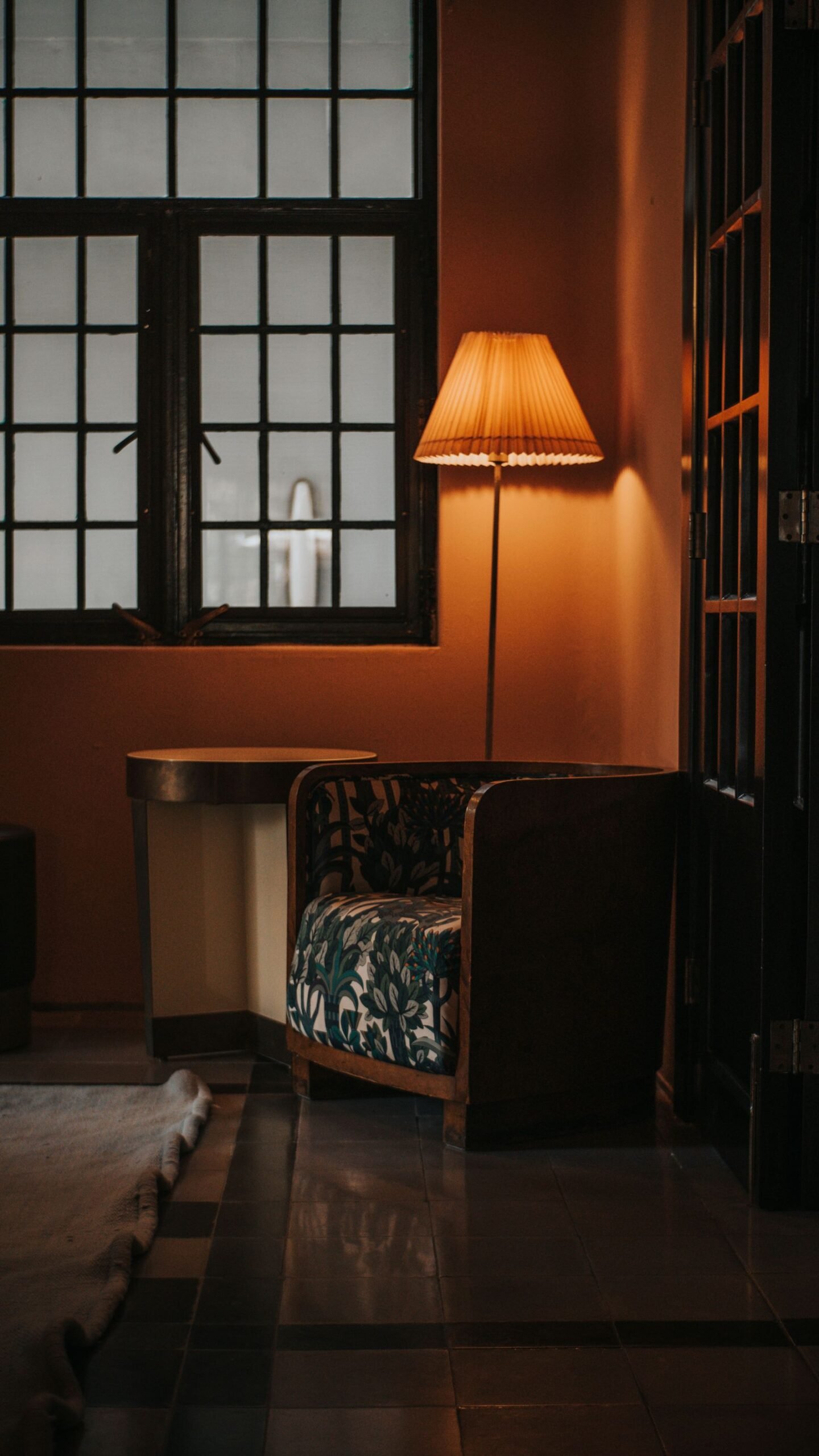 Armchair and lamp in a warm living room corner by a window.