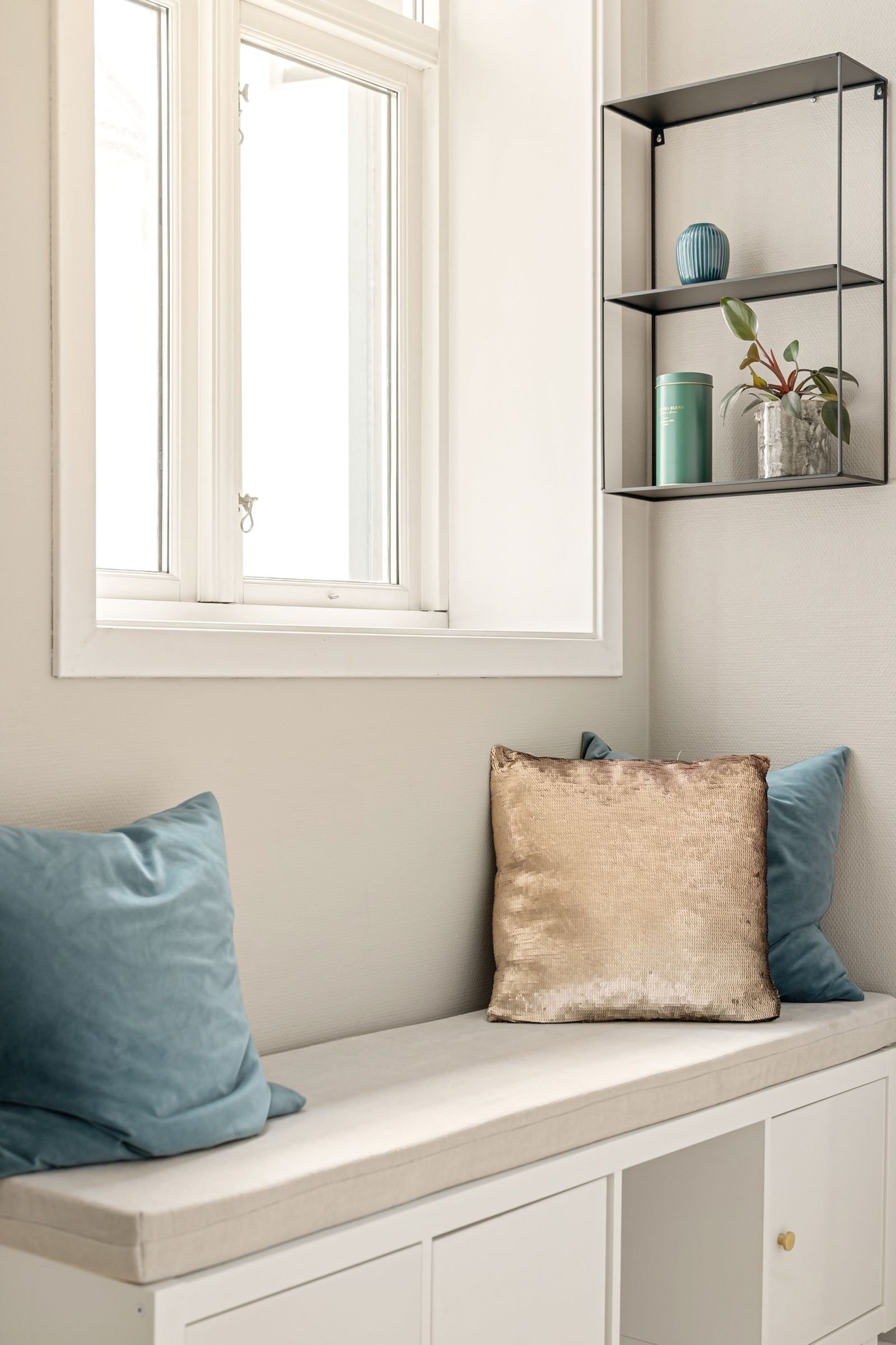 Indoor nook with plush pillows, shelving and soft natural light.