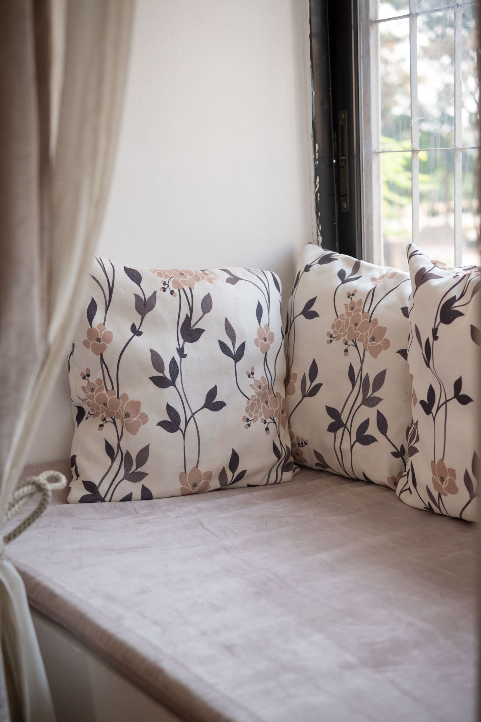 Window nook with floral cushions in a cozy room.