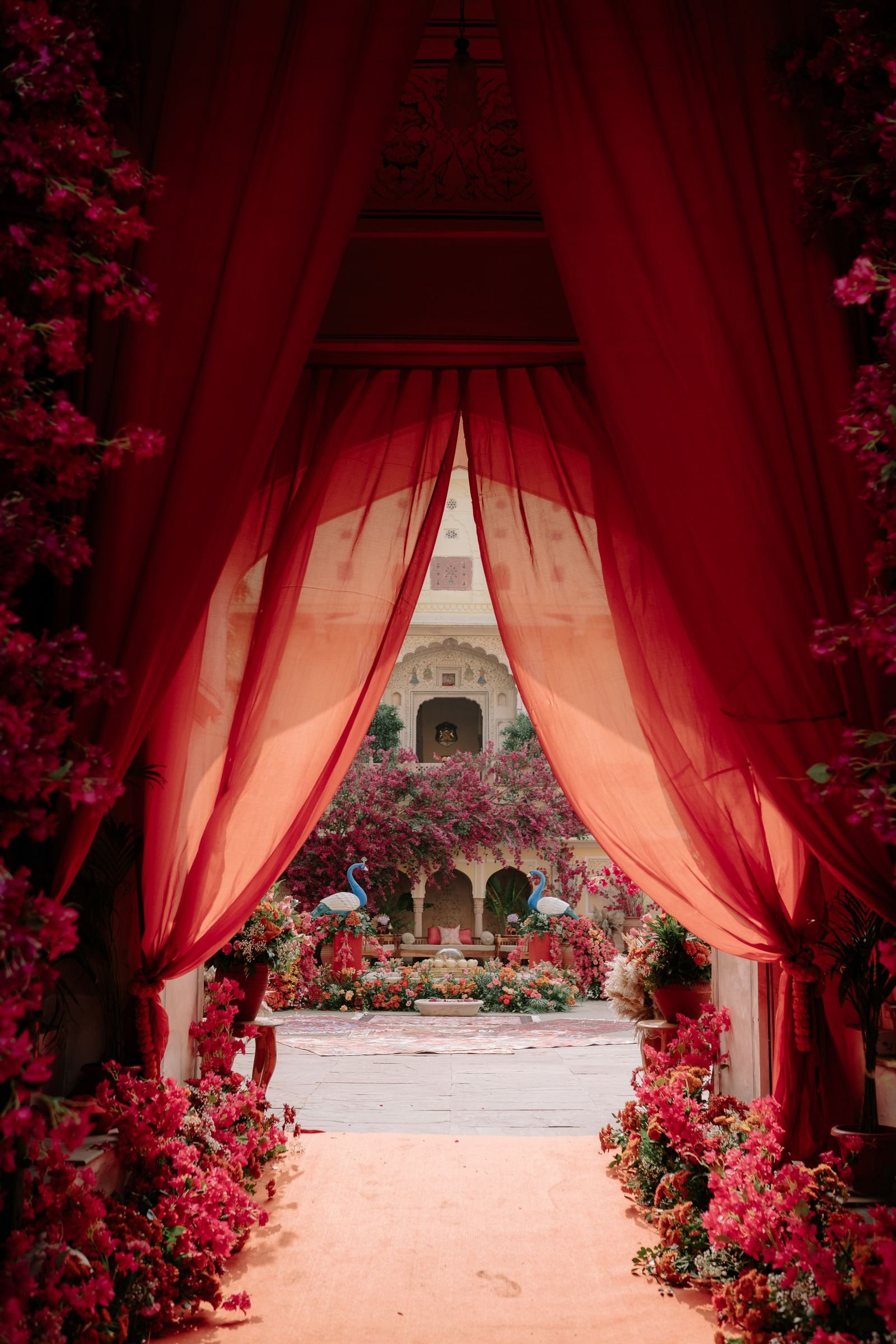 Floral entrance framed by red drapes leading into a garden.