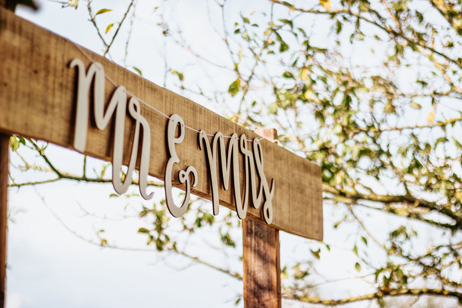 Wooden Mr and Mrs sign hanging outdoors on a sunny day.