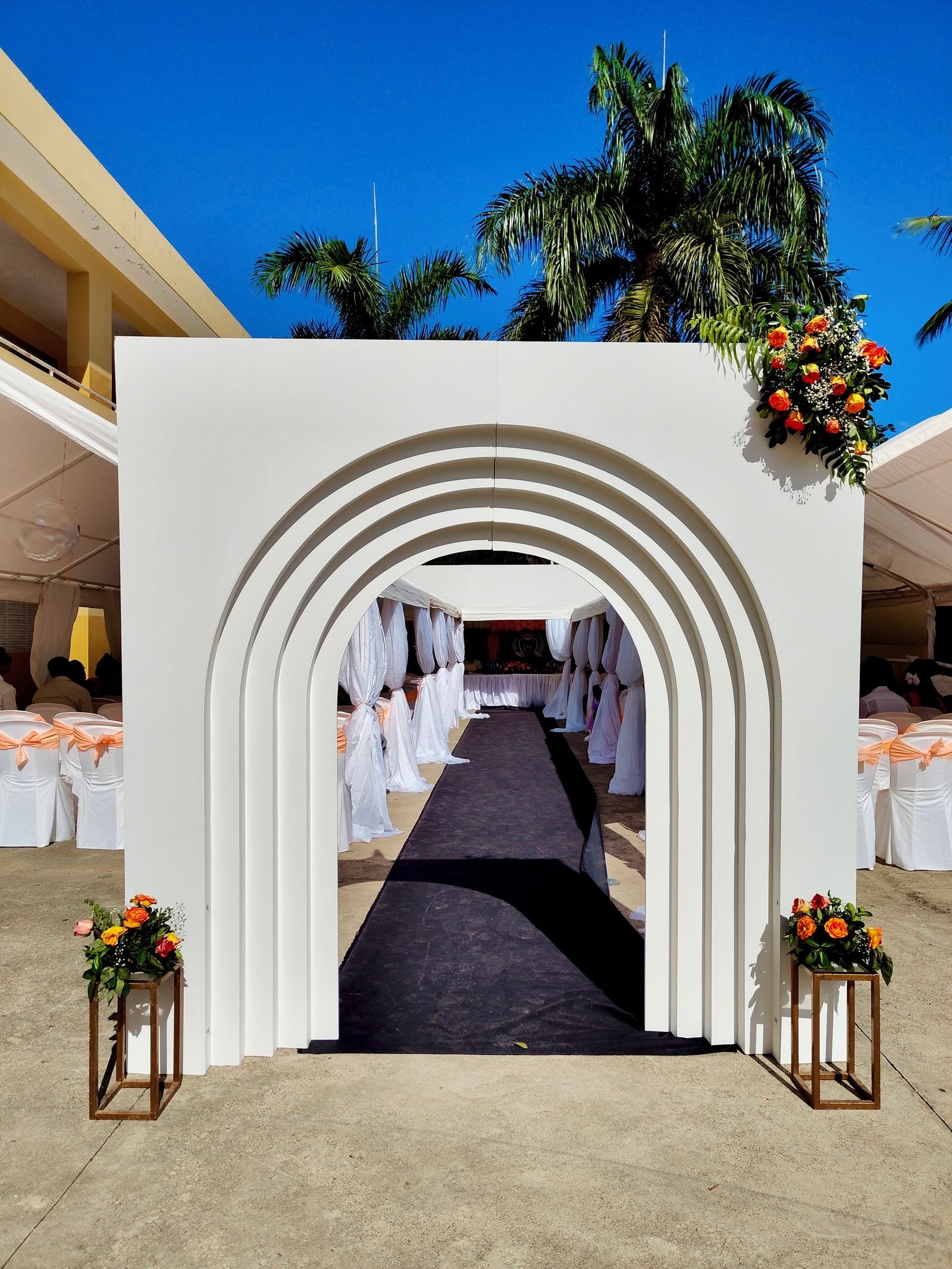 White wedding arch with elegant floral arrangements outdoors.