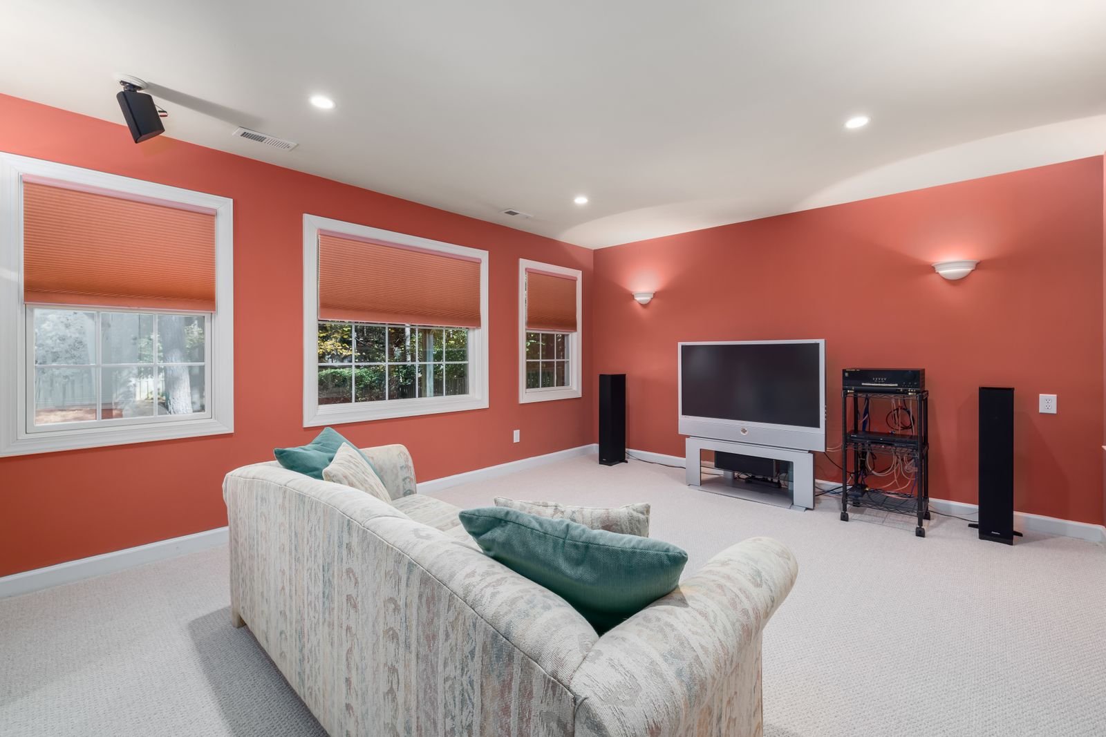 Home theater room with orange walls, a couch and a flat-screen TV.