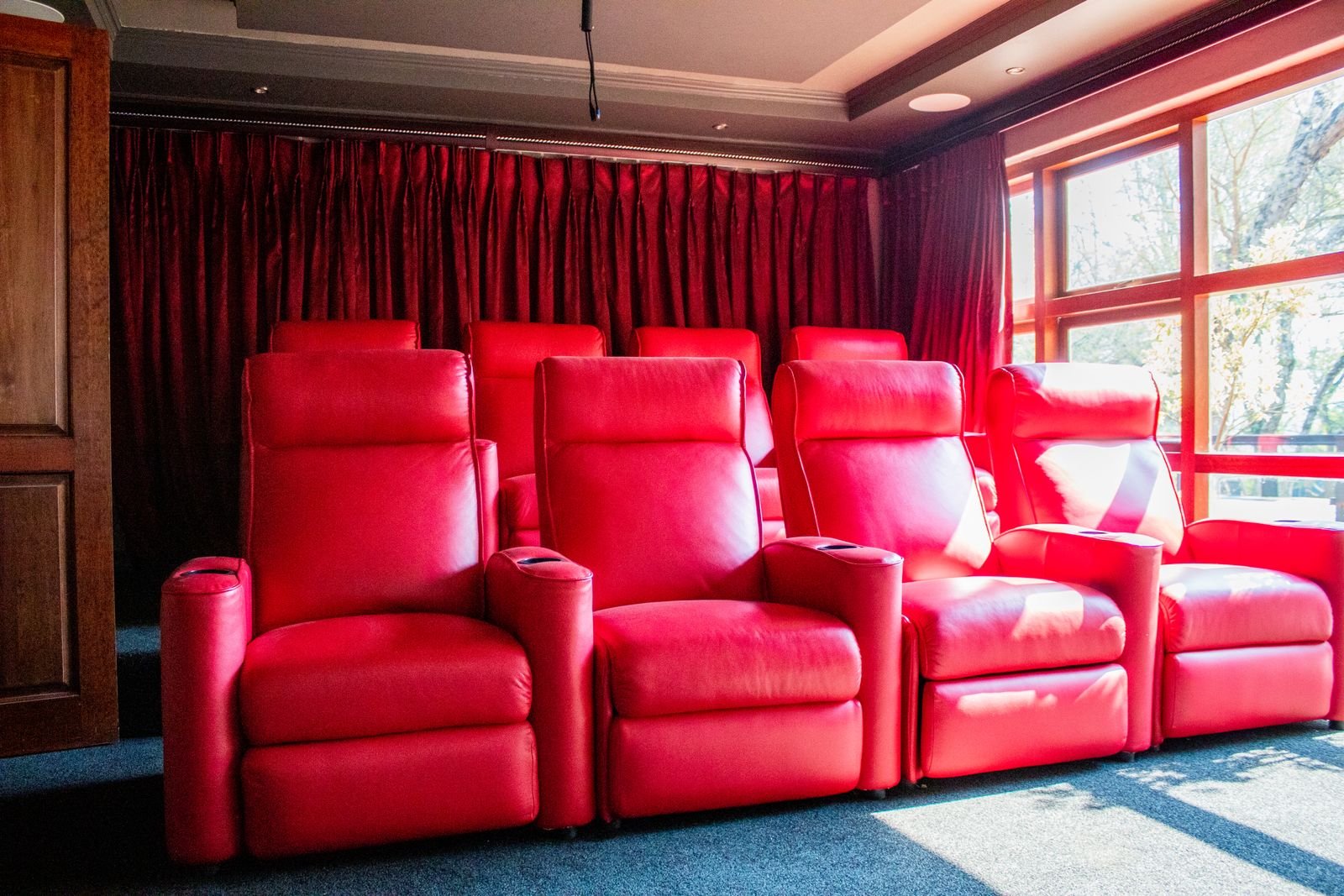 Home theater with red leather reclining chairs and natural light.