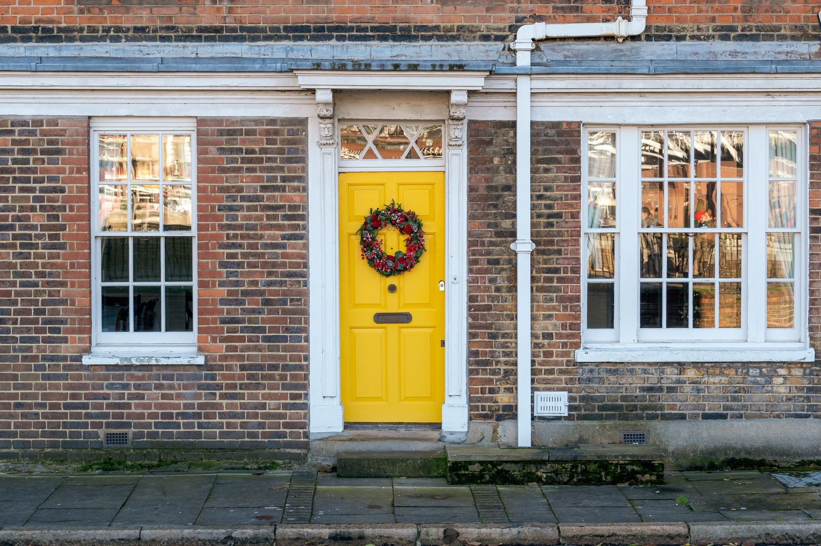 Bright yellow front door with a wreath on a classic brick house facade.