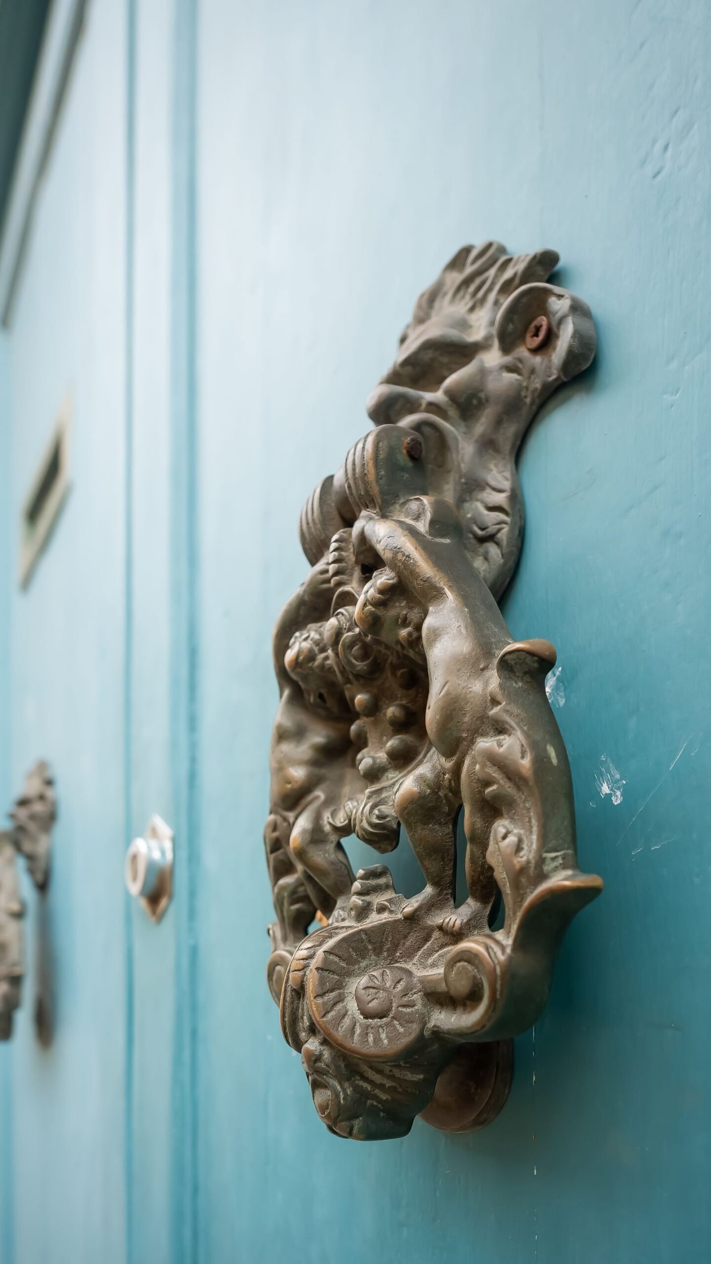 Ornate bronze door knocker on a vivid blue front door.