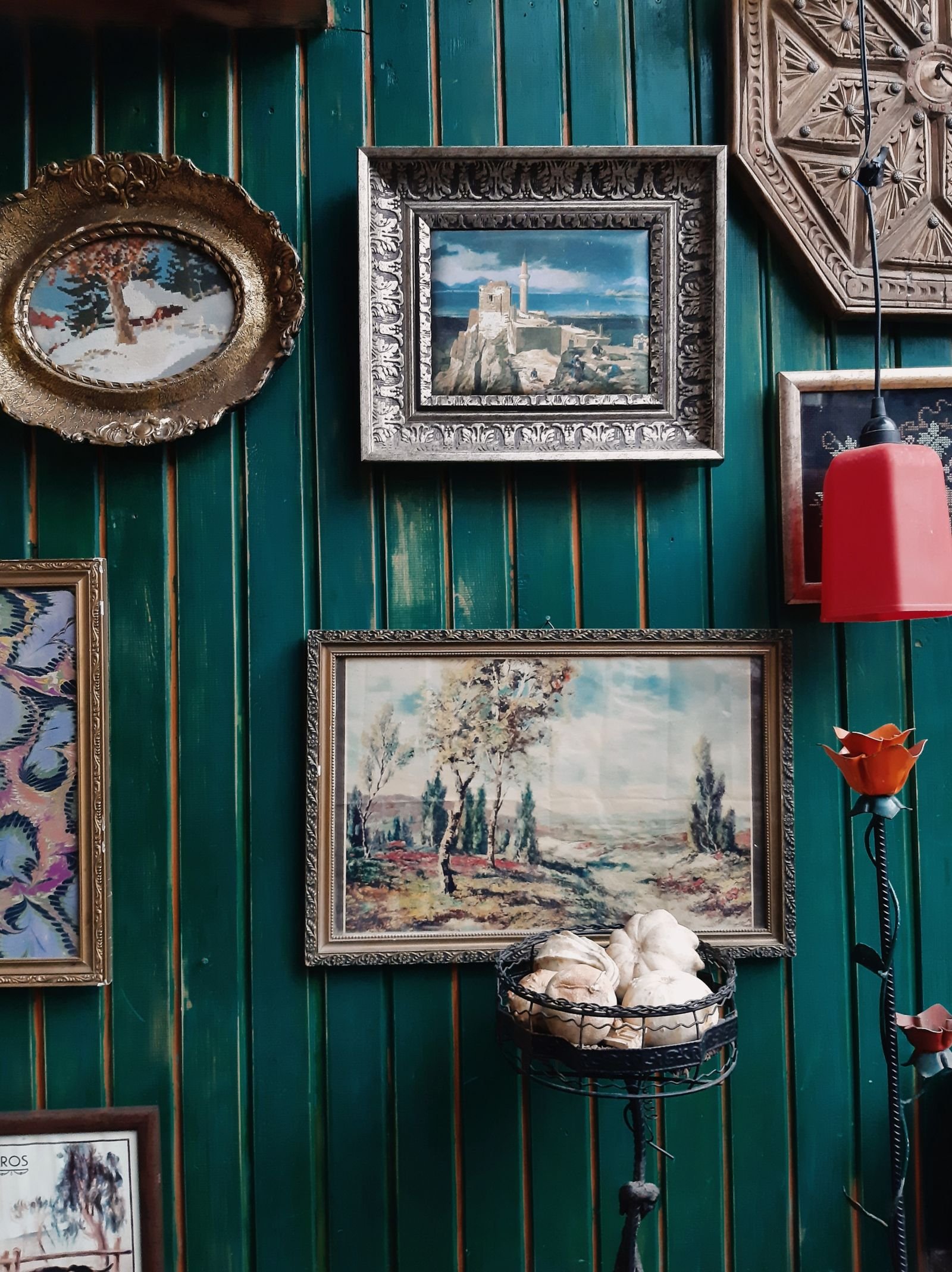 Green wood-paneled wall hung with vintage framed paintings.