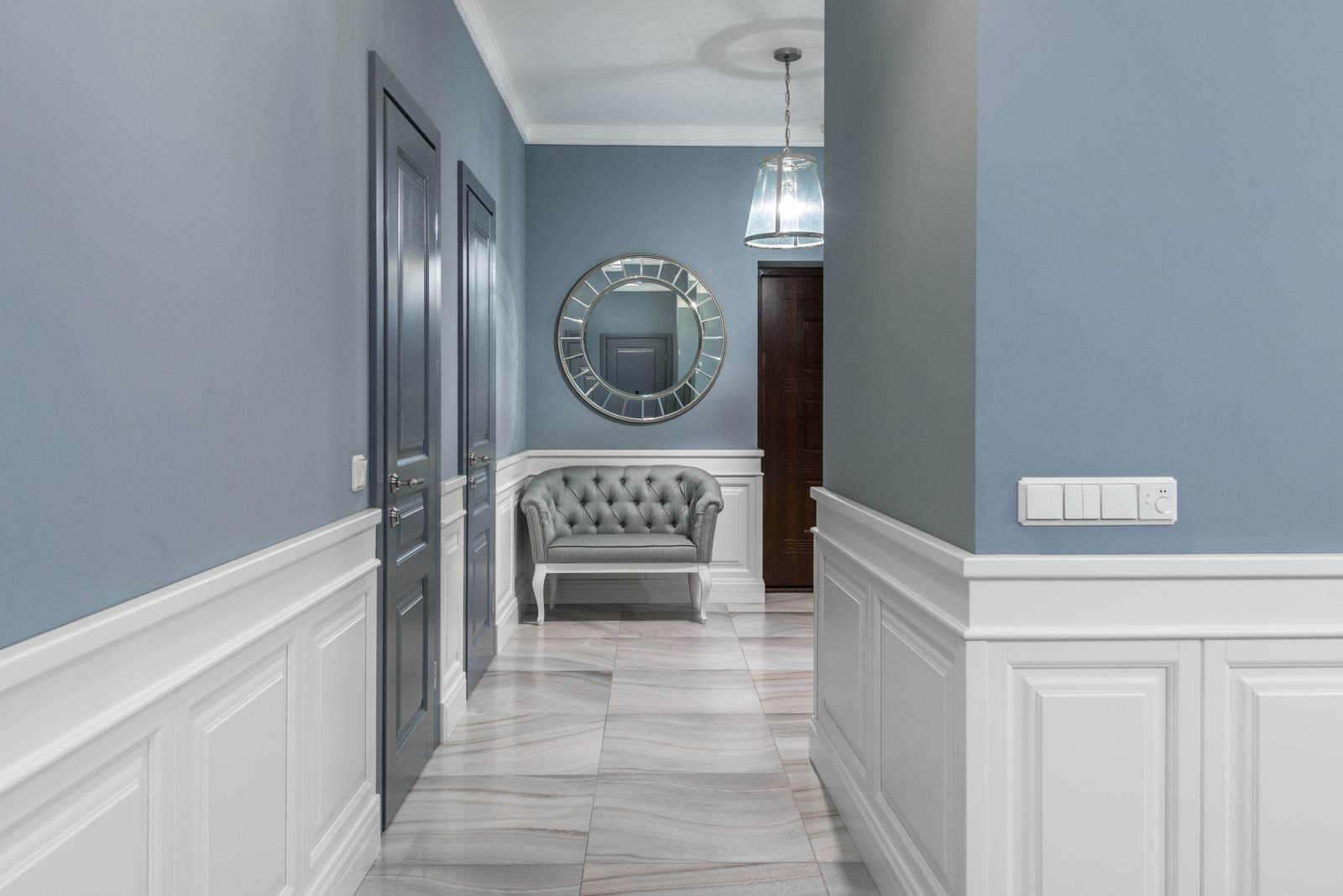 Hallway with an armchair, a decorative mirror and soft lighting.