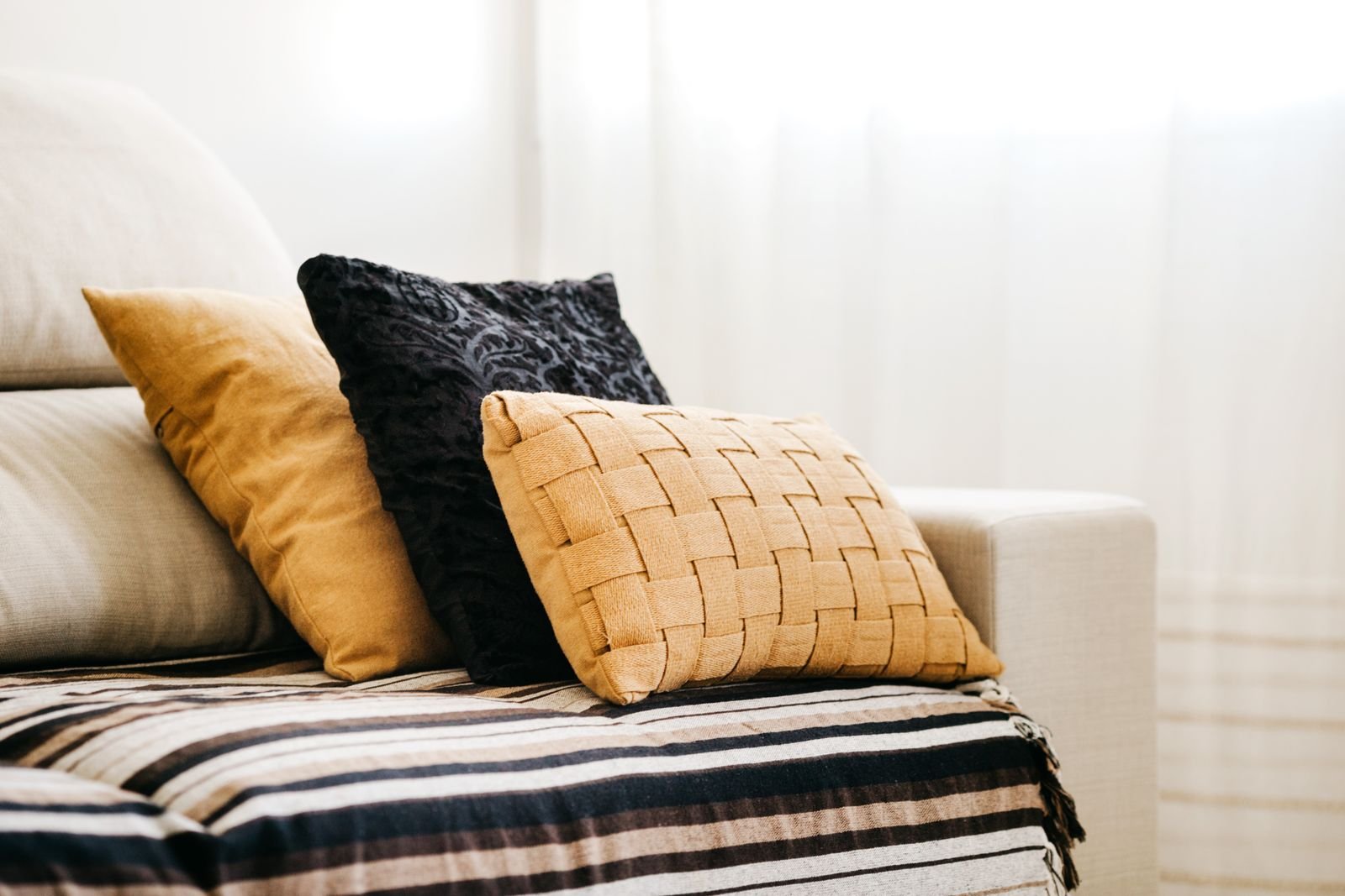 Sofa with decorative pillows and a striped throw in a modern room.
