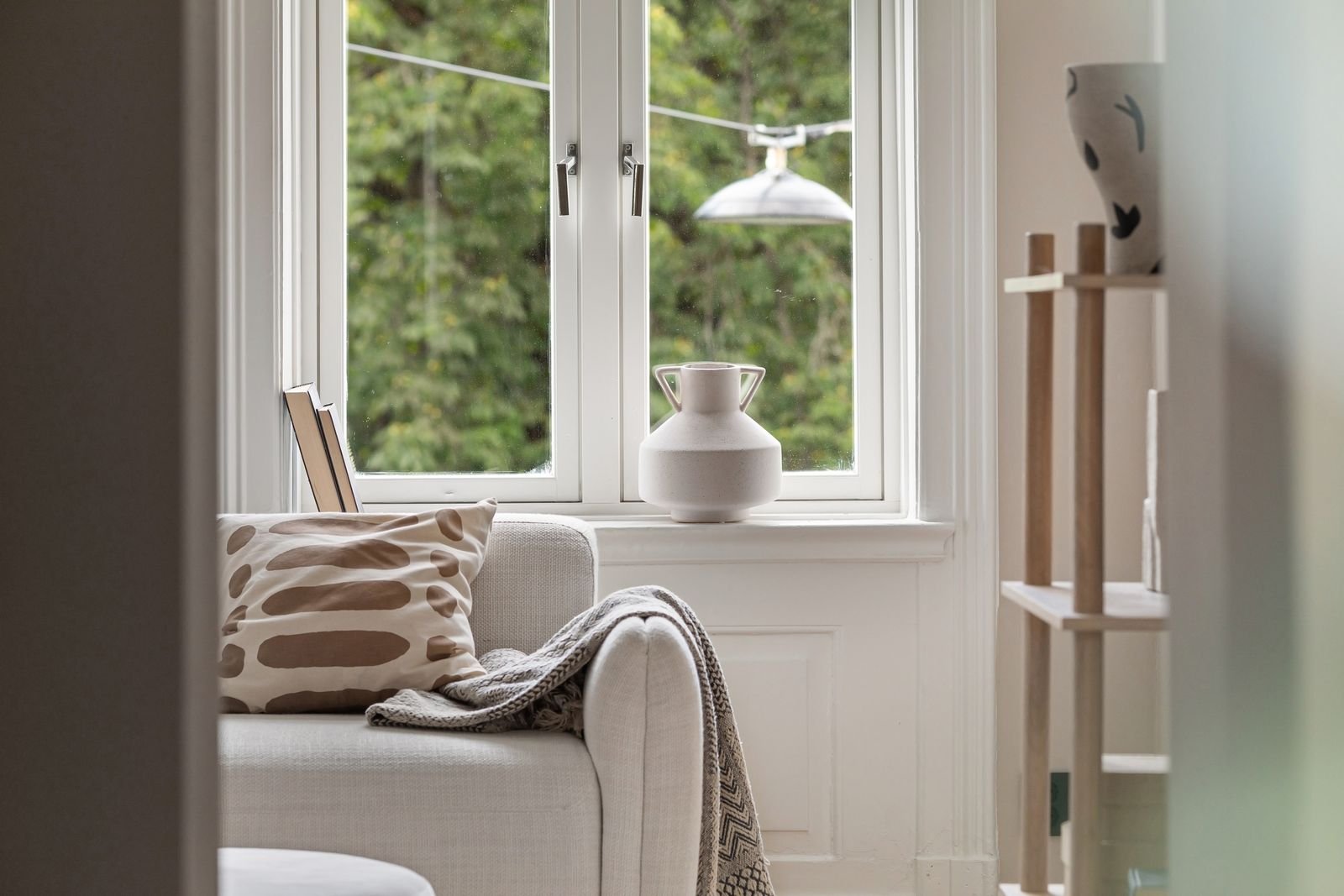 Living room with a comfortable sofa, soft blanket and large windows.