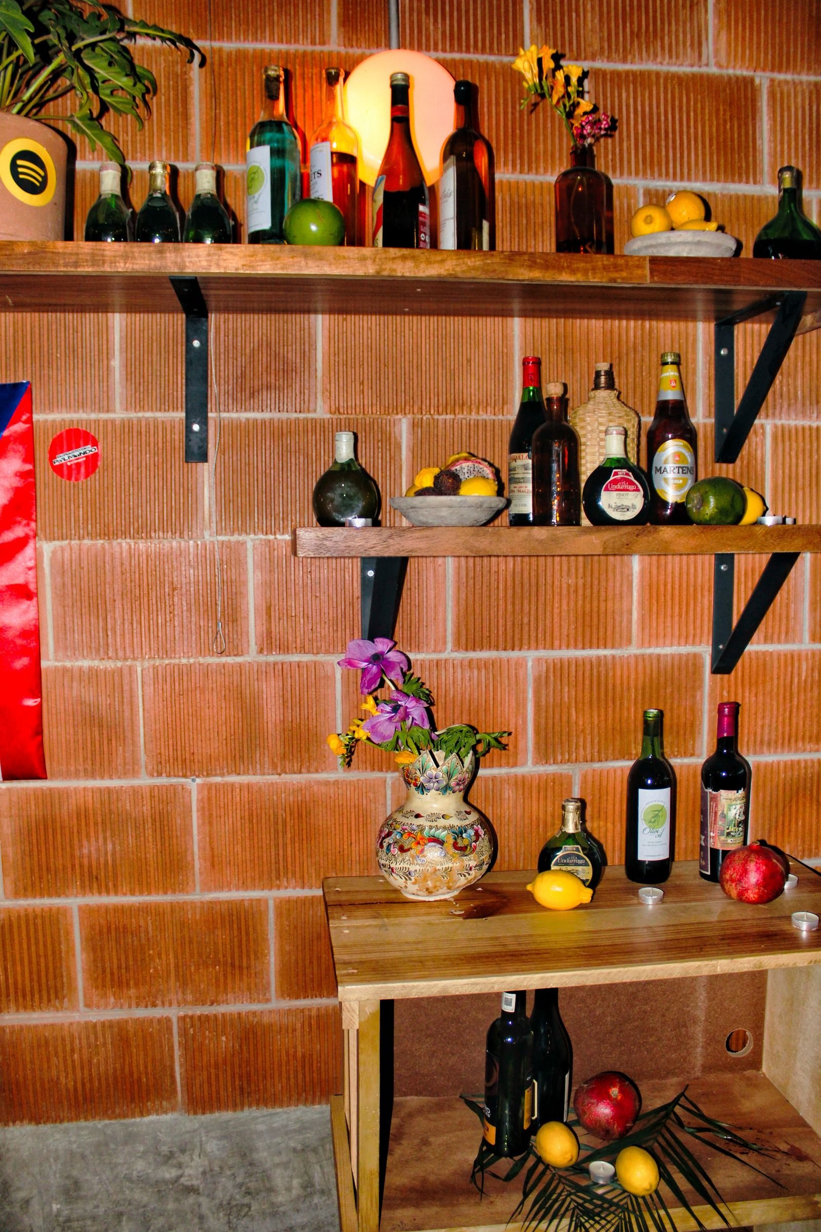 Rustic home bar with bottles and fruit on wooden shelves.