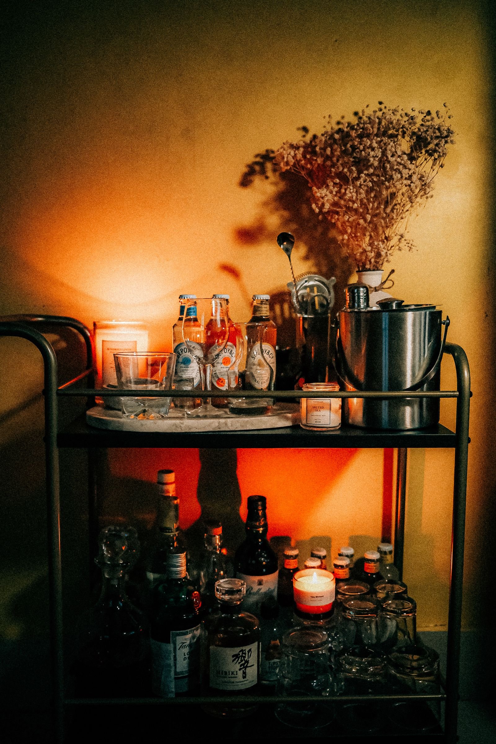 Boho-style bar cart with cocktails under warm lighting.