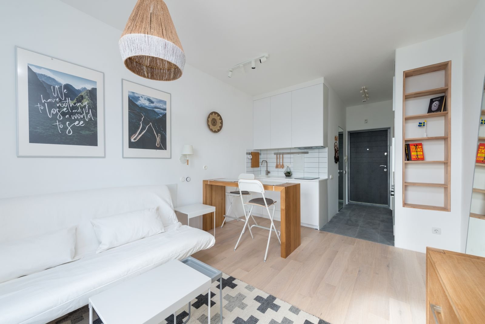 Bright small living room with a white sofa and kitchen area.