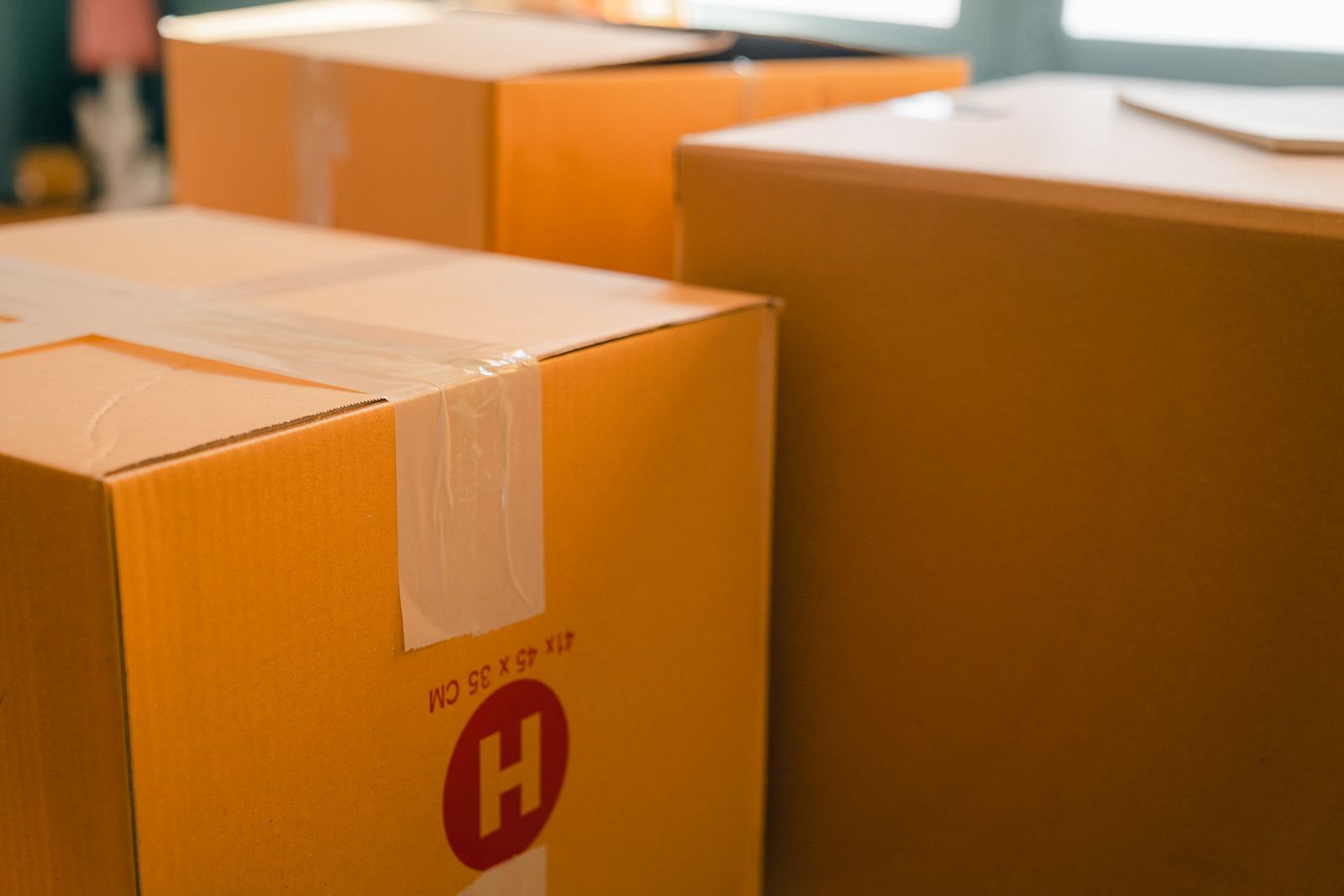 Sealed moving boxes stacked near a window in a sunny room.